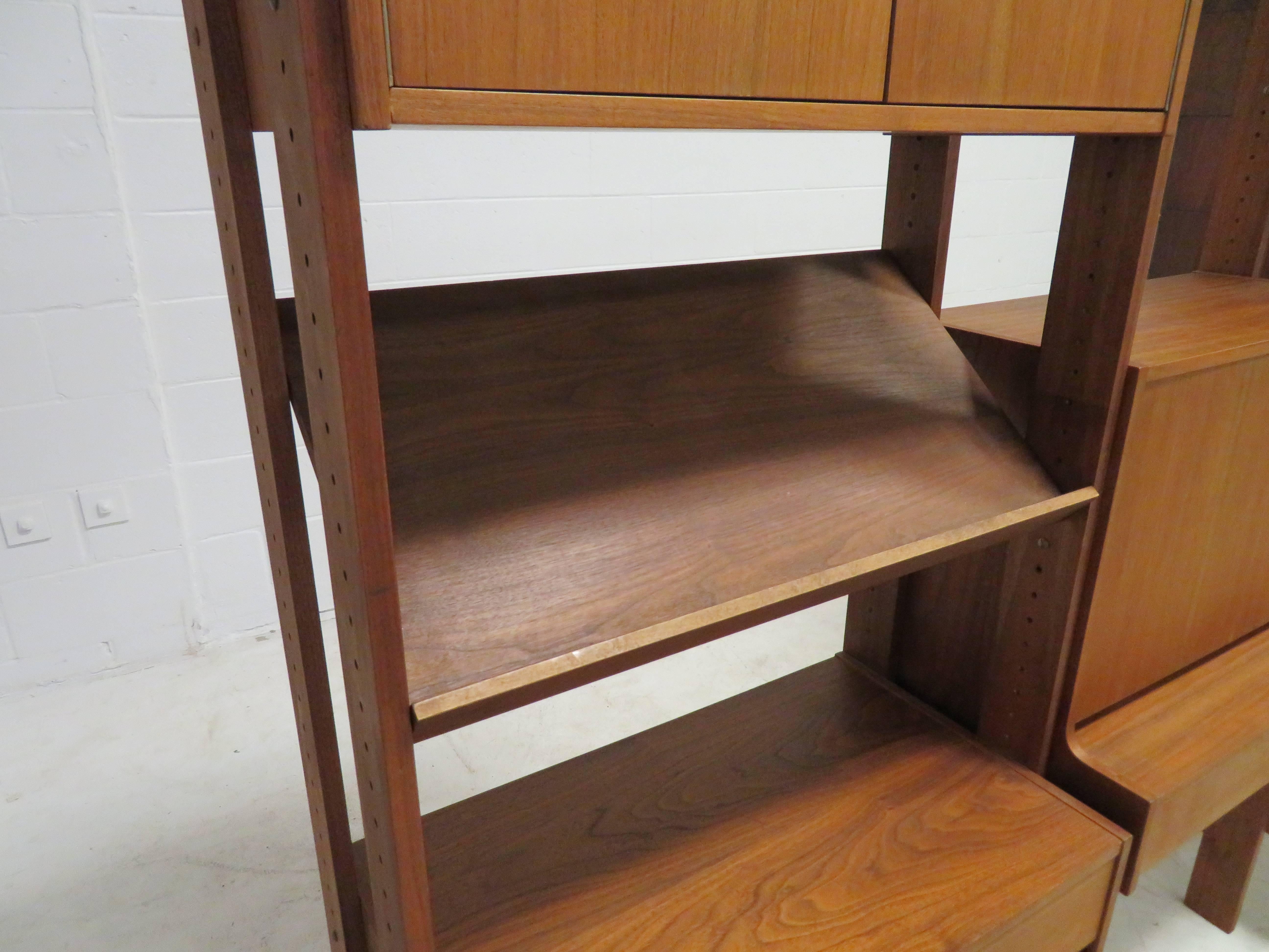 Wonderful Danish modern style three-bay wall unit. This great wall unit is finished on all sides and can be used as a room divider or against the wall. Tons of storage options with drawers, open cabinets and a pull down desk even a slanted shelf for