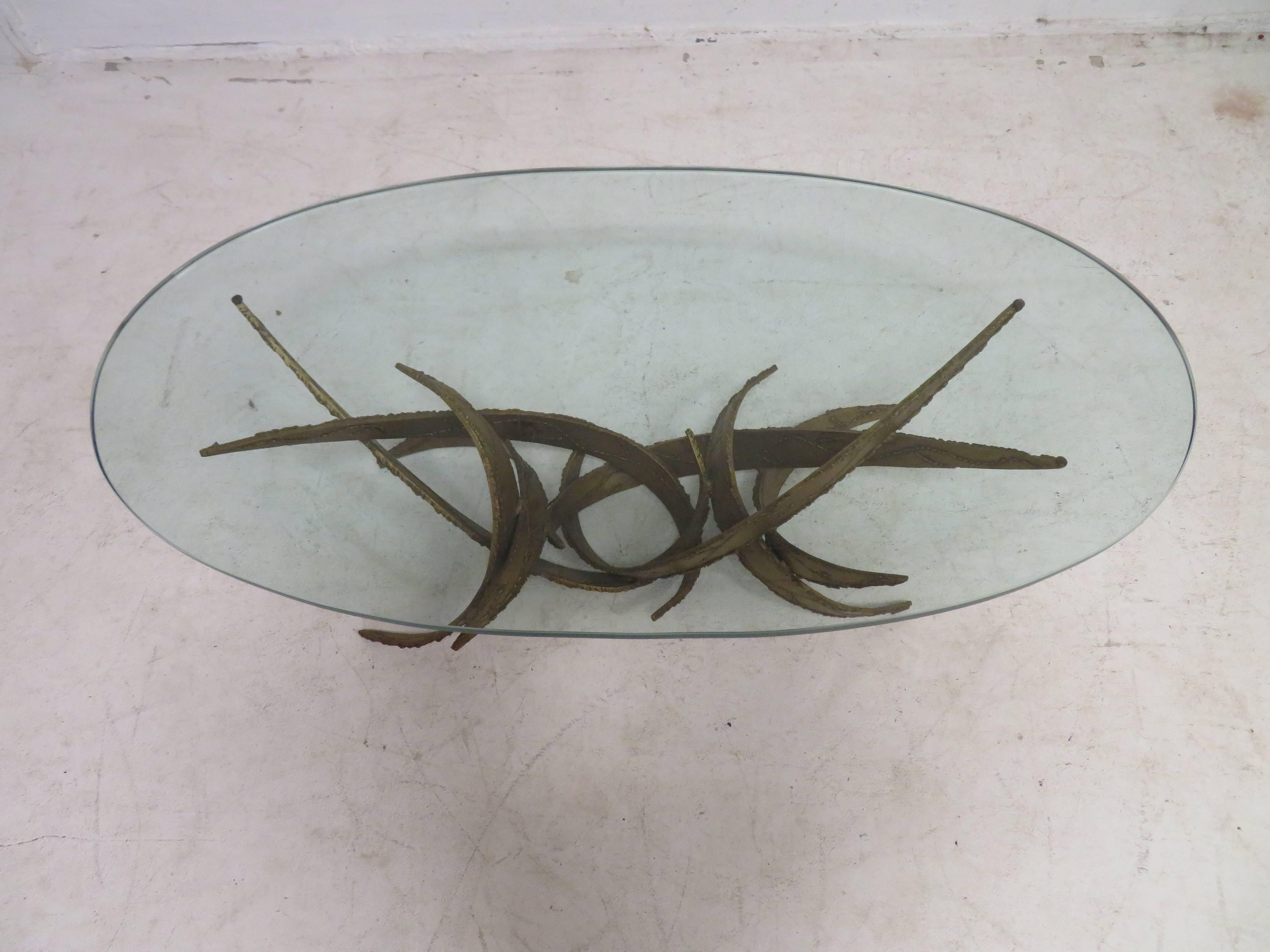 This is an amazing Brutalist glass top coffee or cocktail table of torch-cut steel with a gold base in the style of Silas Seandel.