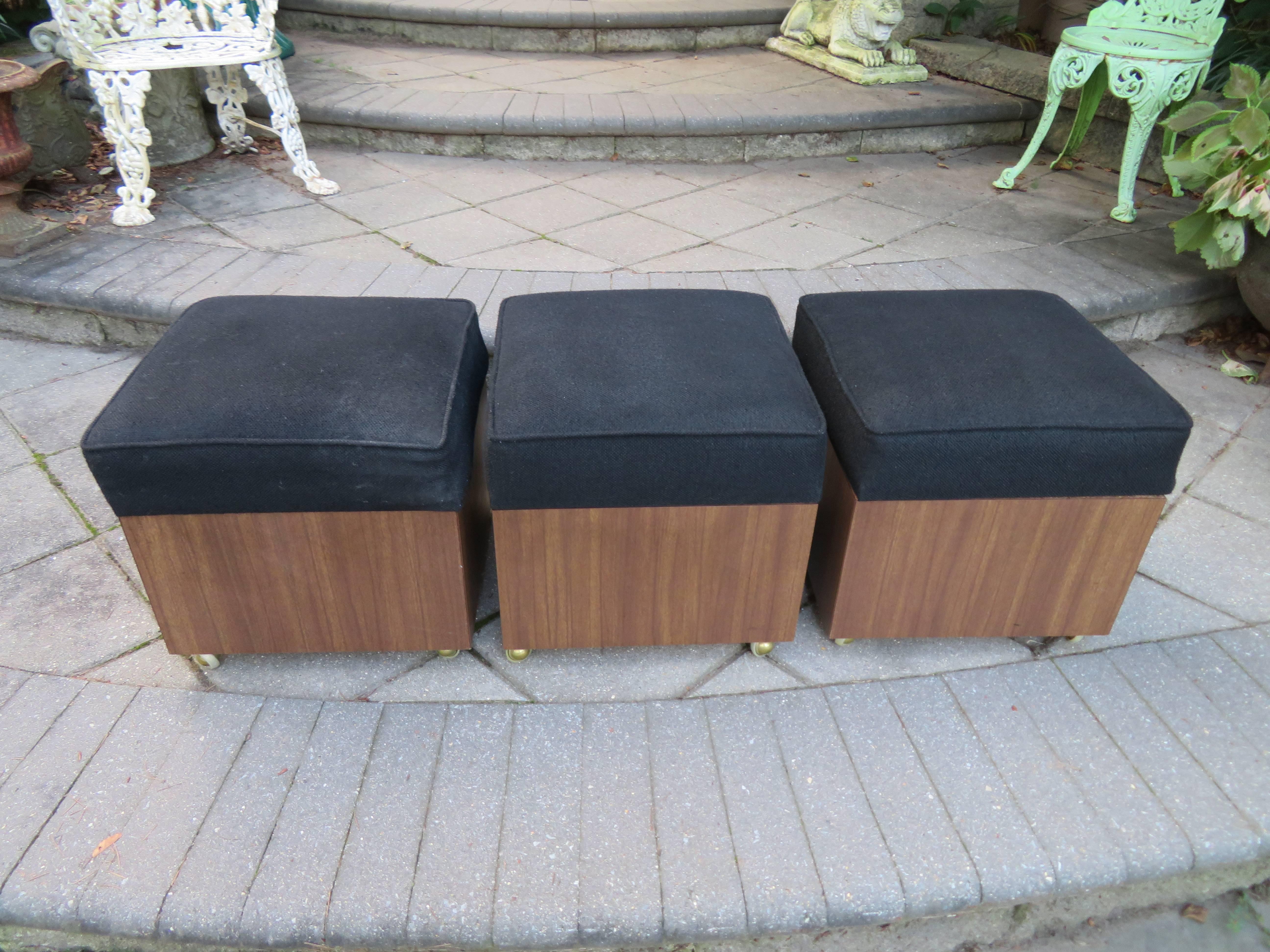Great set of three Mid-Century Modern rolling storage cube stools. Each stool has a thick black wool seat pad that lifts off to reveal a great space for storage-magazines or toys. Rolling cases are laminated with wood grain Formica and look great.