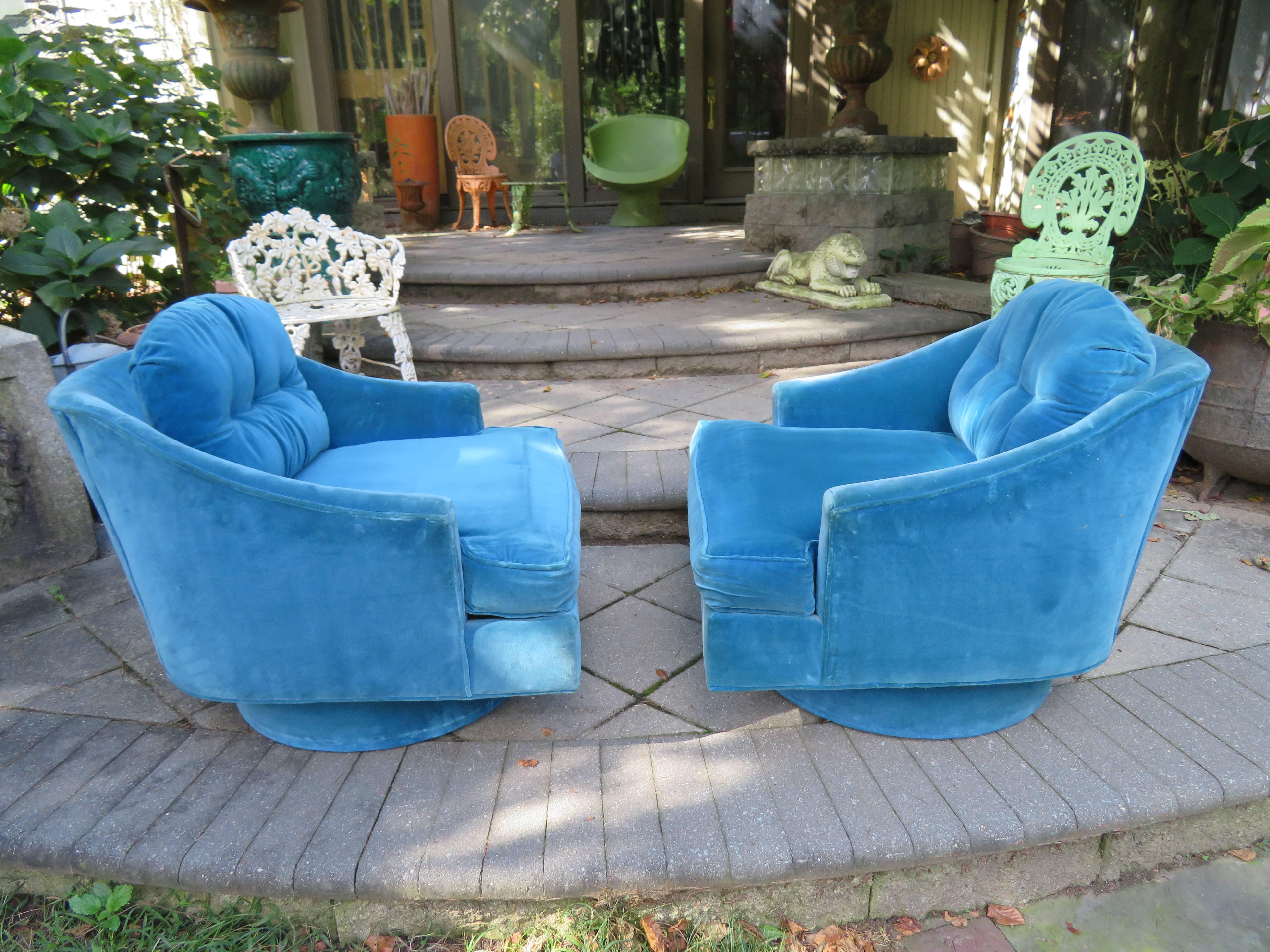 Striking pair of Selig wide barrel back swivel lounge chairs. We love the low slung arms with the wide deep seat-very comfortable. Upholstered in their original blue velvet-reupholstery recommended.