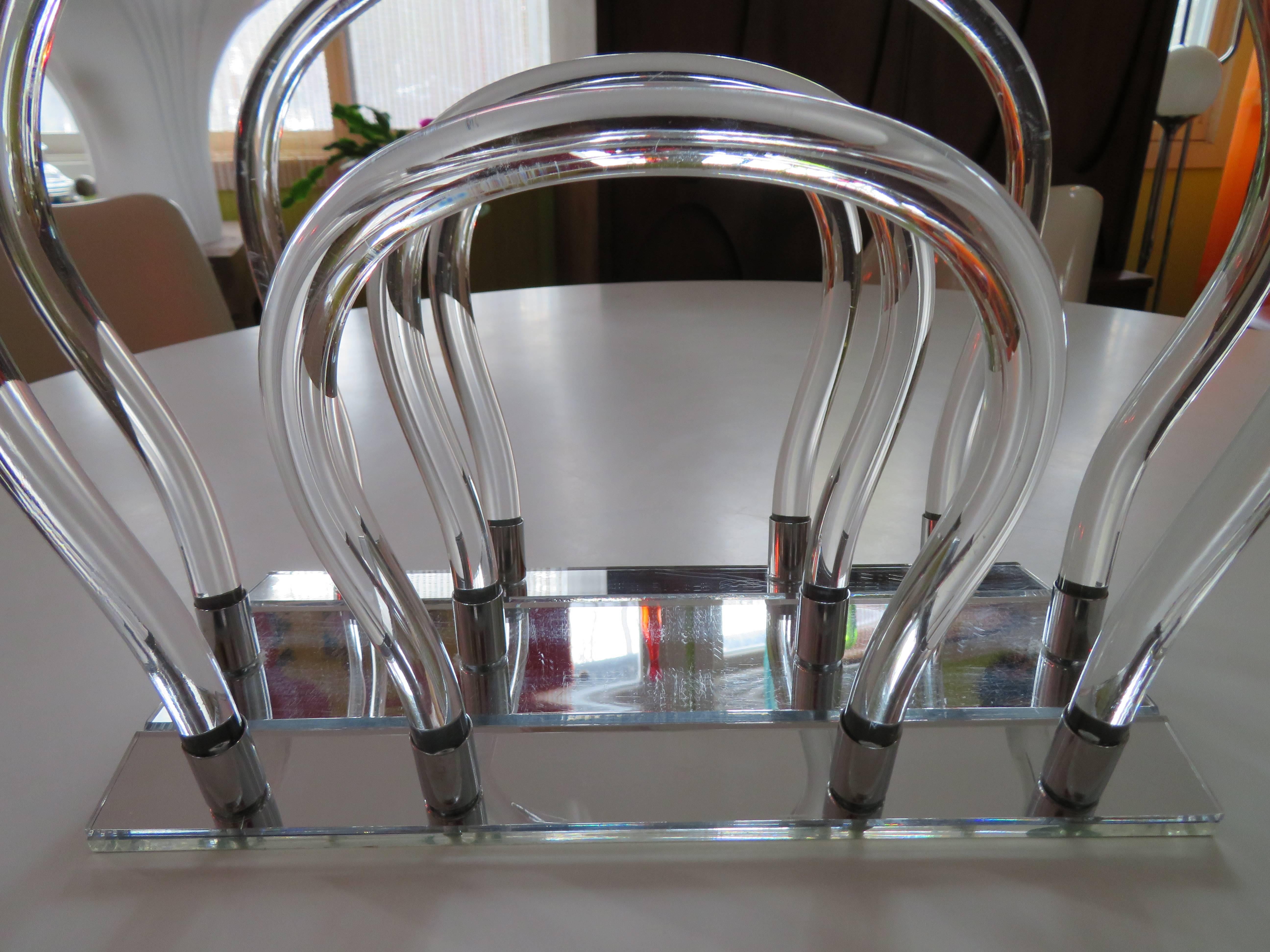 Lucite, chrome and mirror sculptural magazine rack featuring mirrored base that holds twelve chrome sockets into which the Lucite uprights are secured.