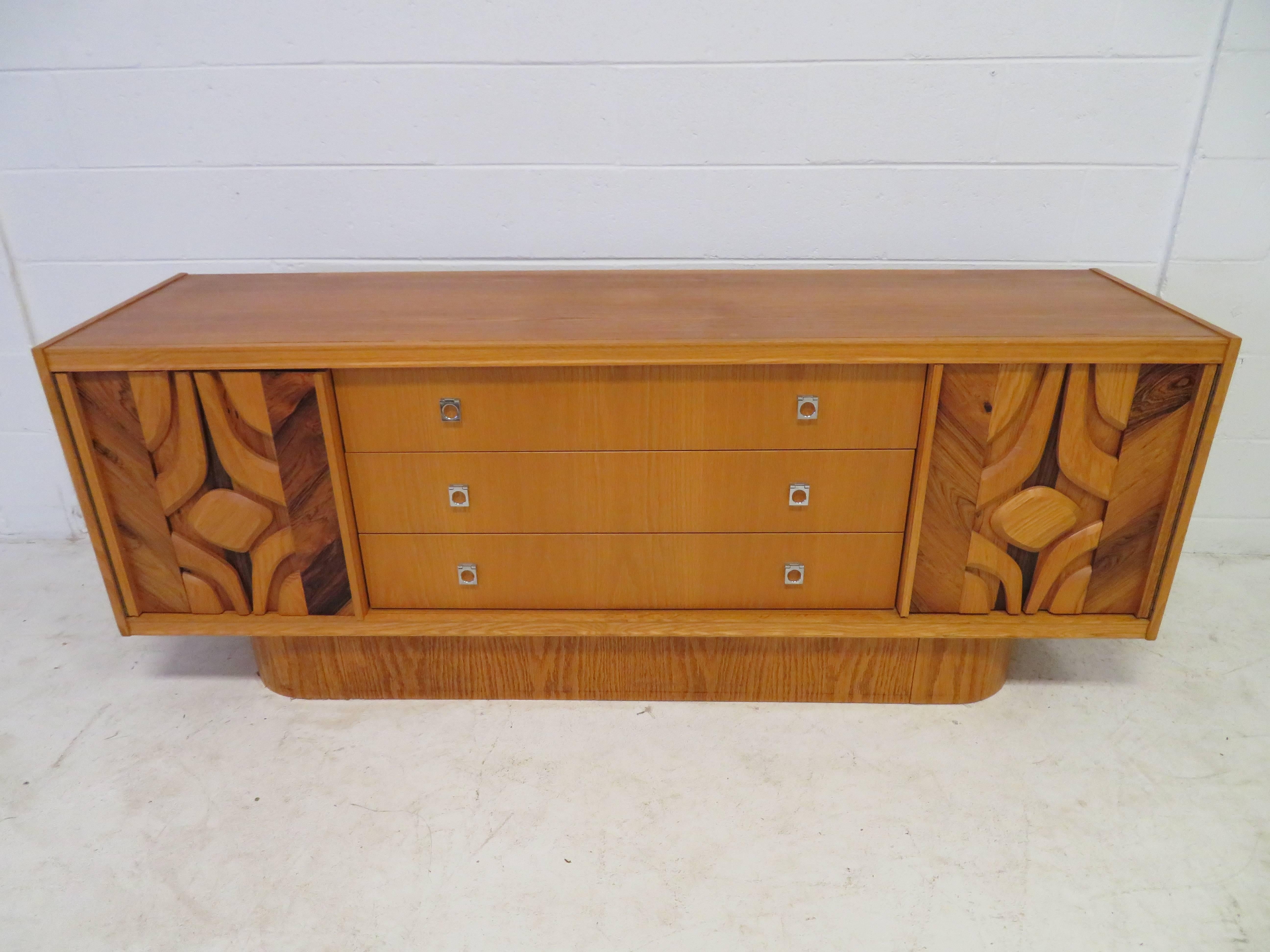 Unusual sculptural front-light wood credenza. This piece not only has great style but has tons of storage options-three long drawers and doors that open to reveal one adjustable shelf on each side.