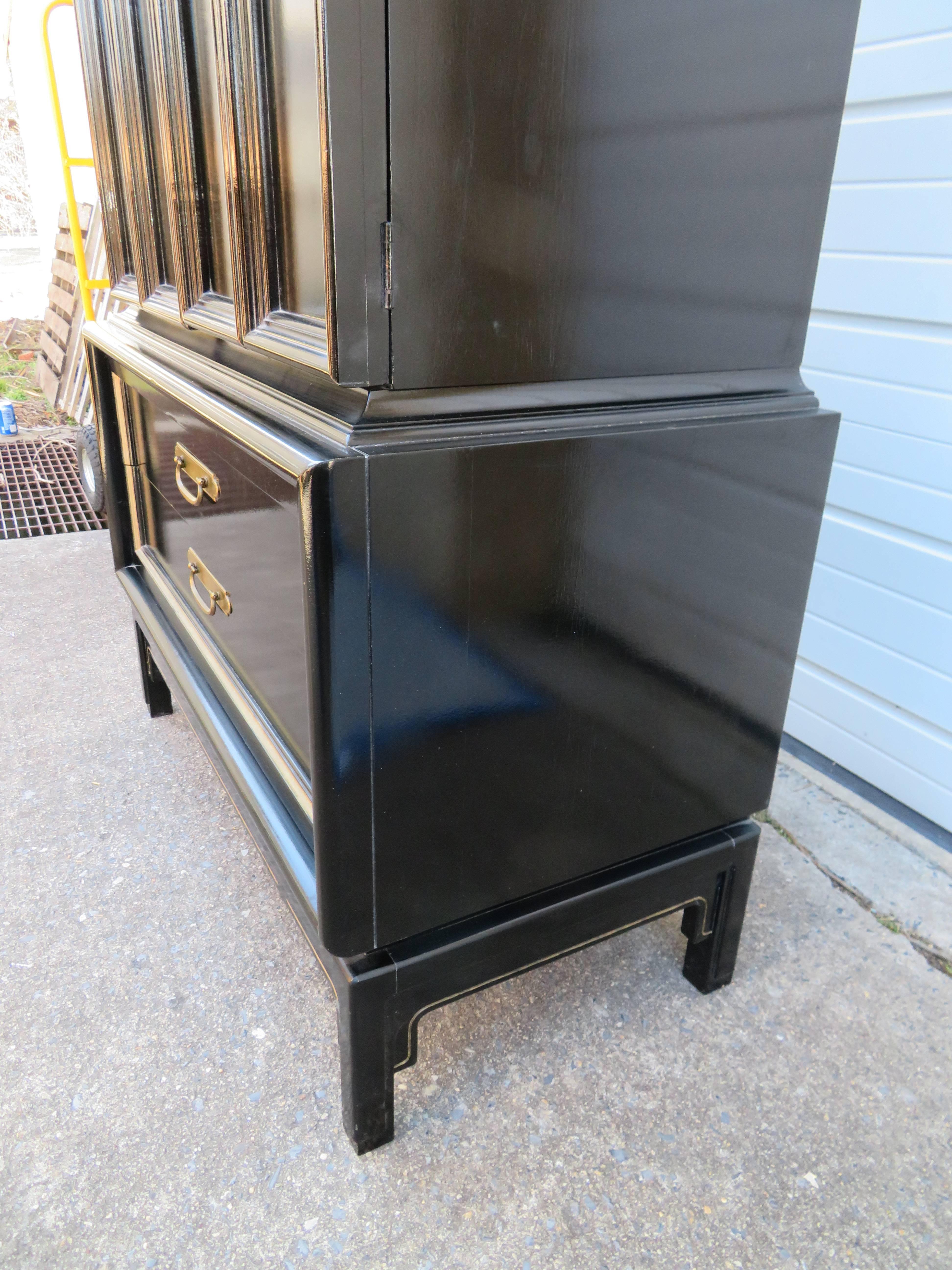 Stunning chinoiserie style black lacquered tall dresser. Check out all the storage options behind those doors-boy they sure don't make pieces like this anymore! We love all the brass and gold details-just fabulous.