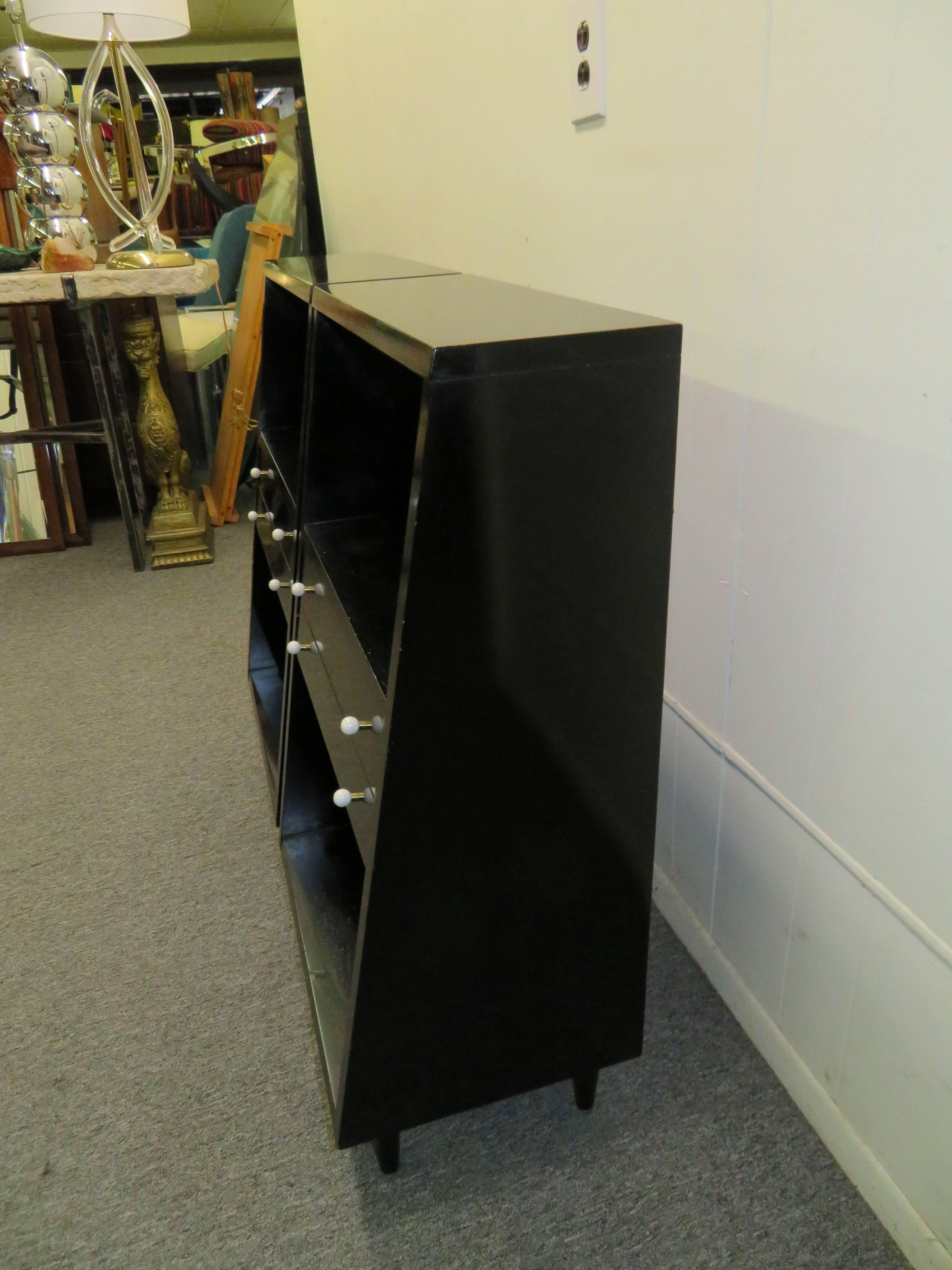 Handsome pair of American of Martinsville black lacquered nightstands with round white ceramic pulls. We love the interesting shape of these being tall and smaller at the top with a wider bottom. These will need to be re-lacquered as they have some