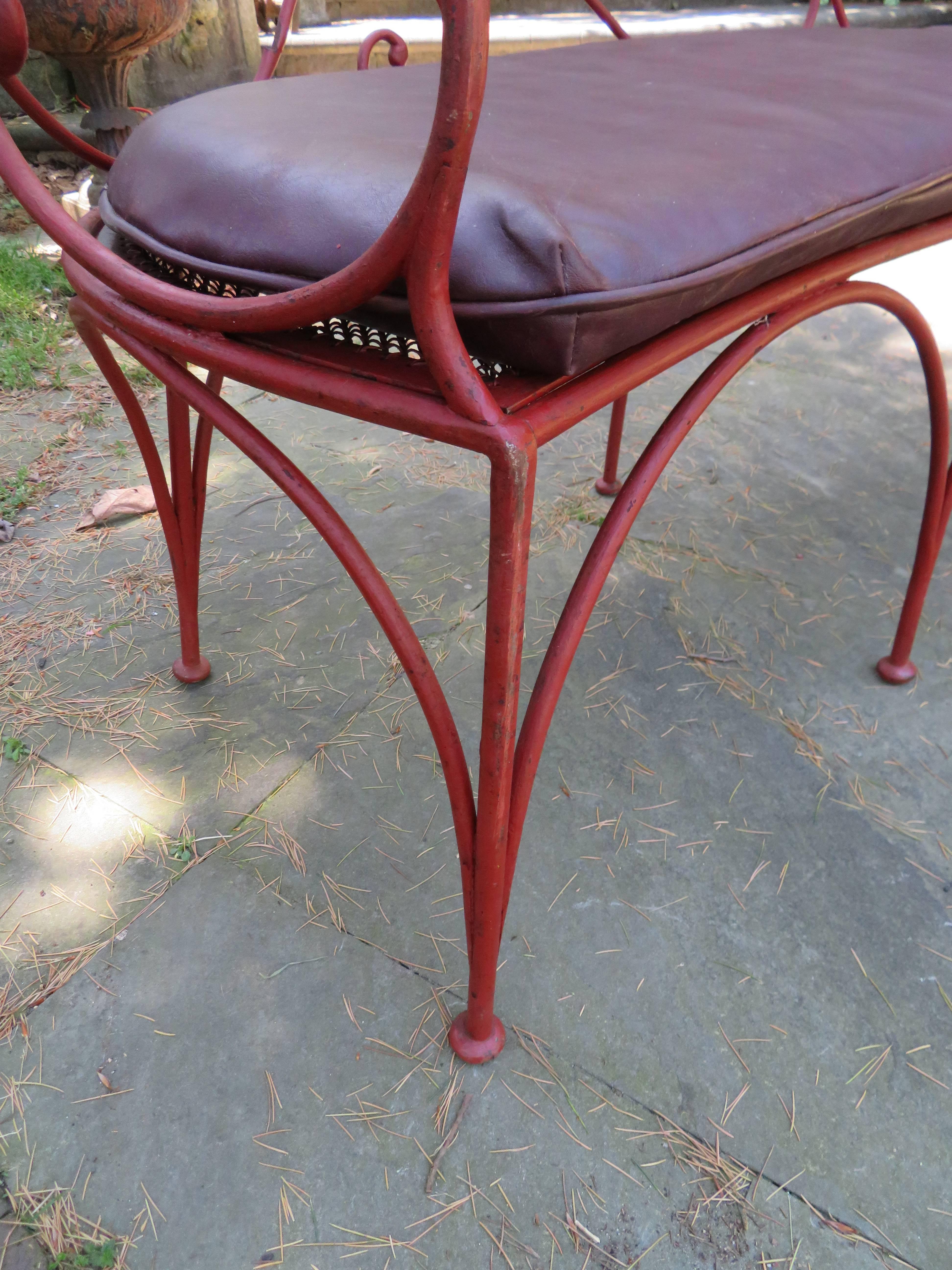 Charming curved iron scroll garden bench with original pad.