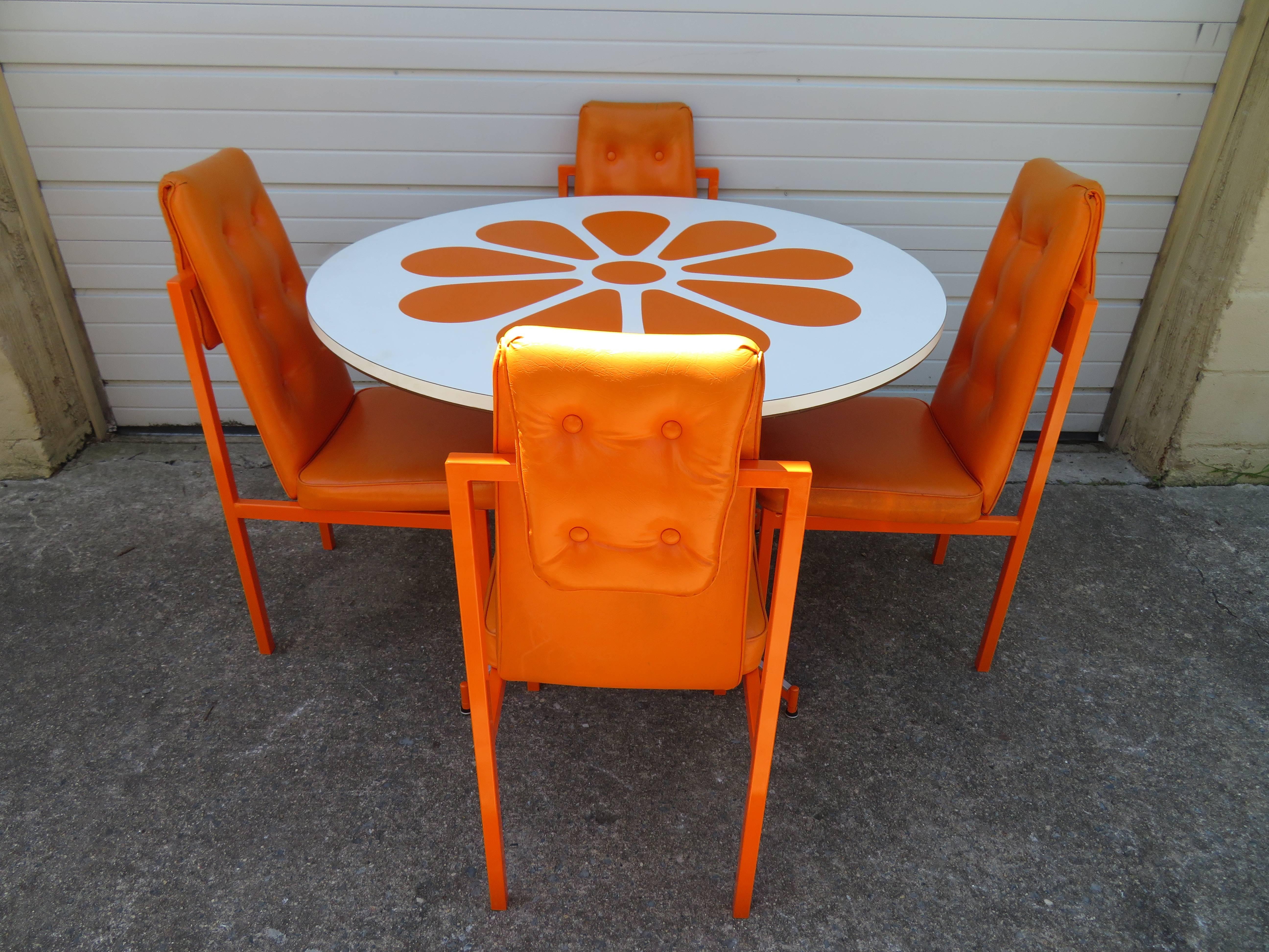 Magnifique ensemble de quatre chaises de salle à manger amusantes avec une table de salle à manger orange à fleurs en tranches assortie. Tous les cadres métalliques ont été fraîchement recouverts d'une peinture en poudre de la même couleur qu'à