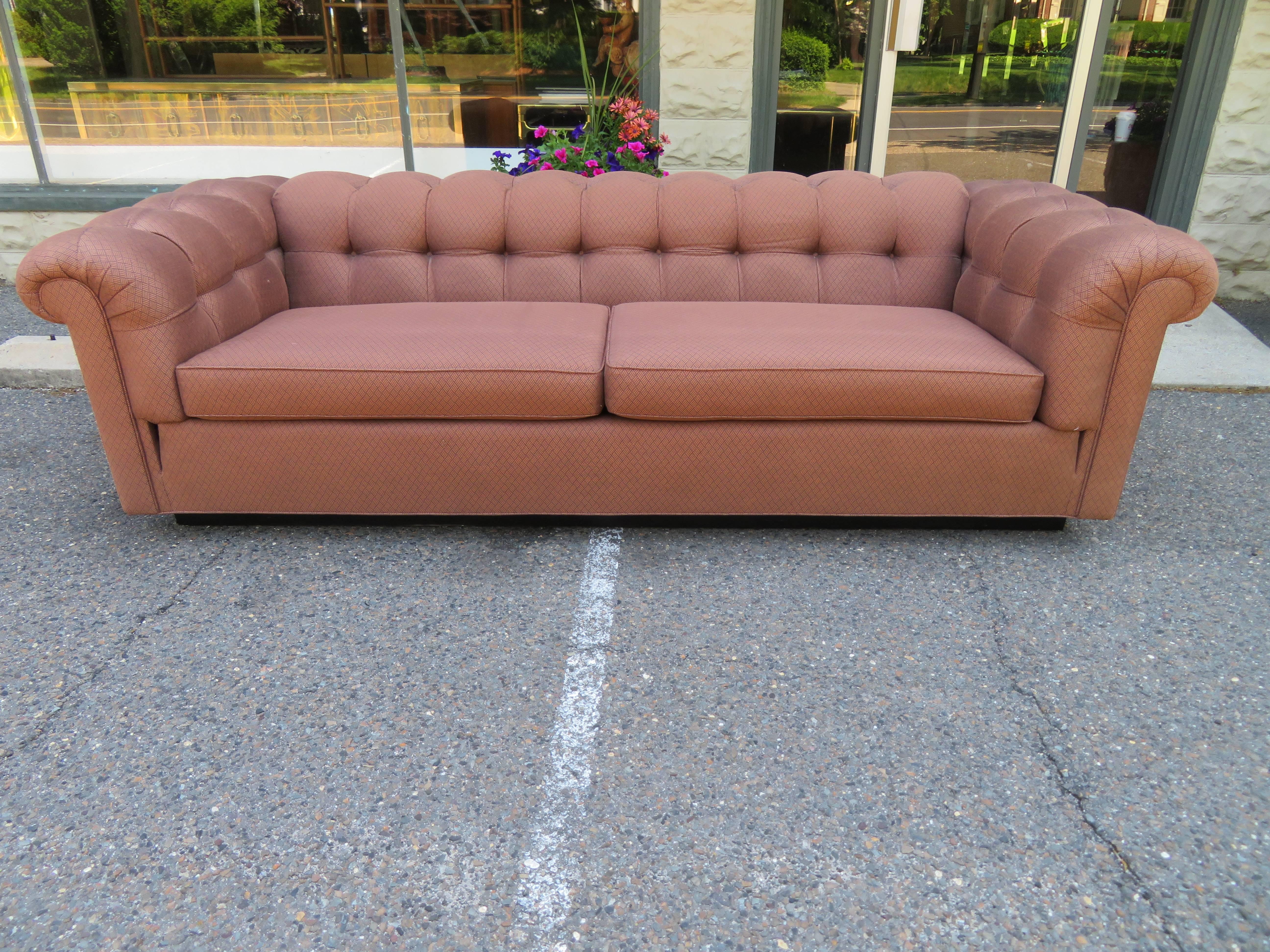 Handsome Dunbar style tufted Chesterfield party sofa. We love the thick squarish rolled arms and back with ebonized black plinth base-re-upholstery is recommended.