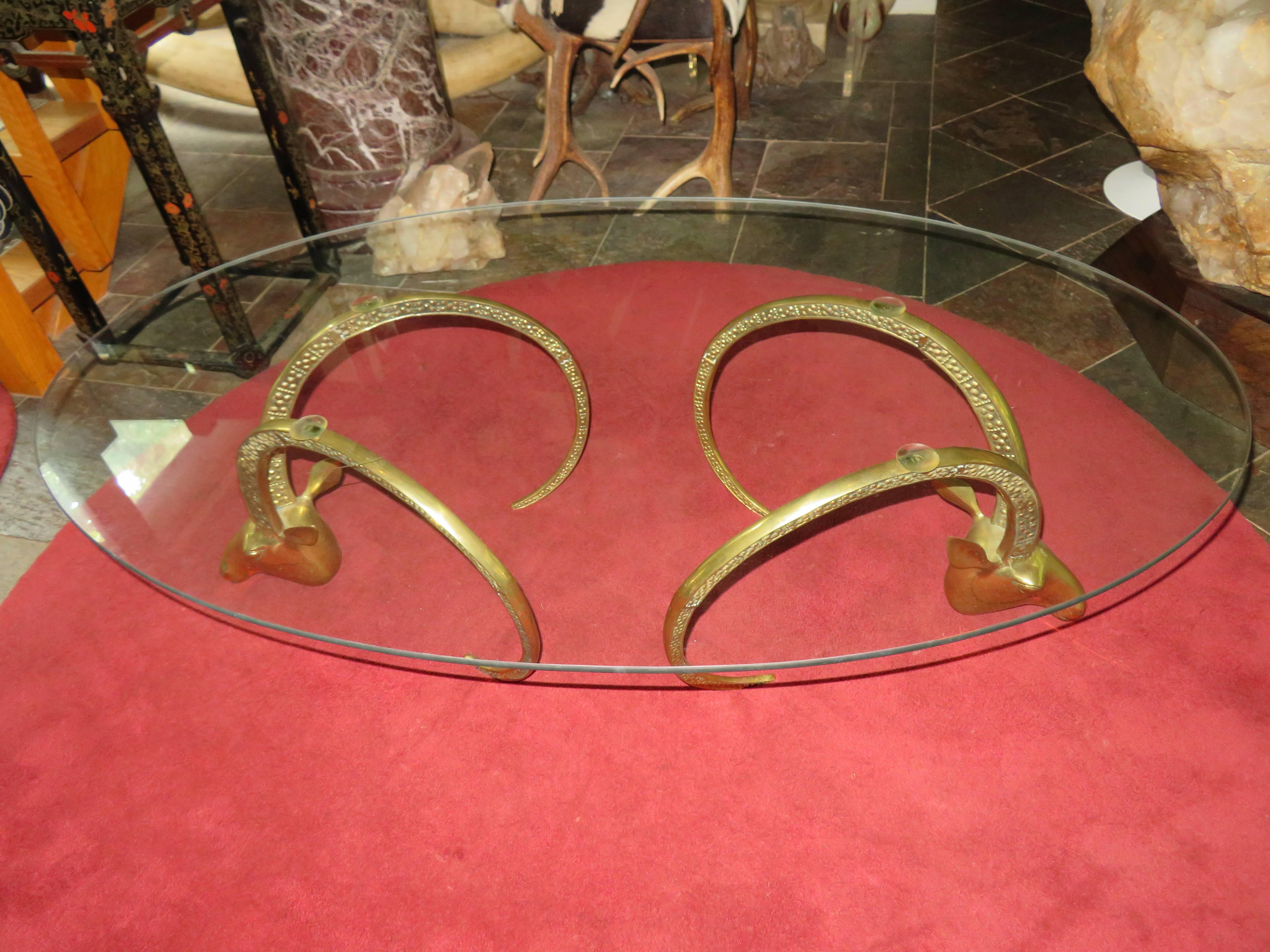 Magnificent brass ibex ram head coffee table. We do have two pairs of these ram heads so one giant table can be made with a large glass top or two normal size coffee tables like pictured. We are selling the tables individually but email for special