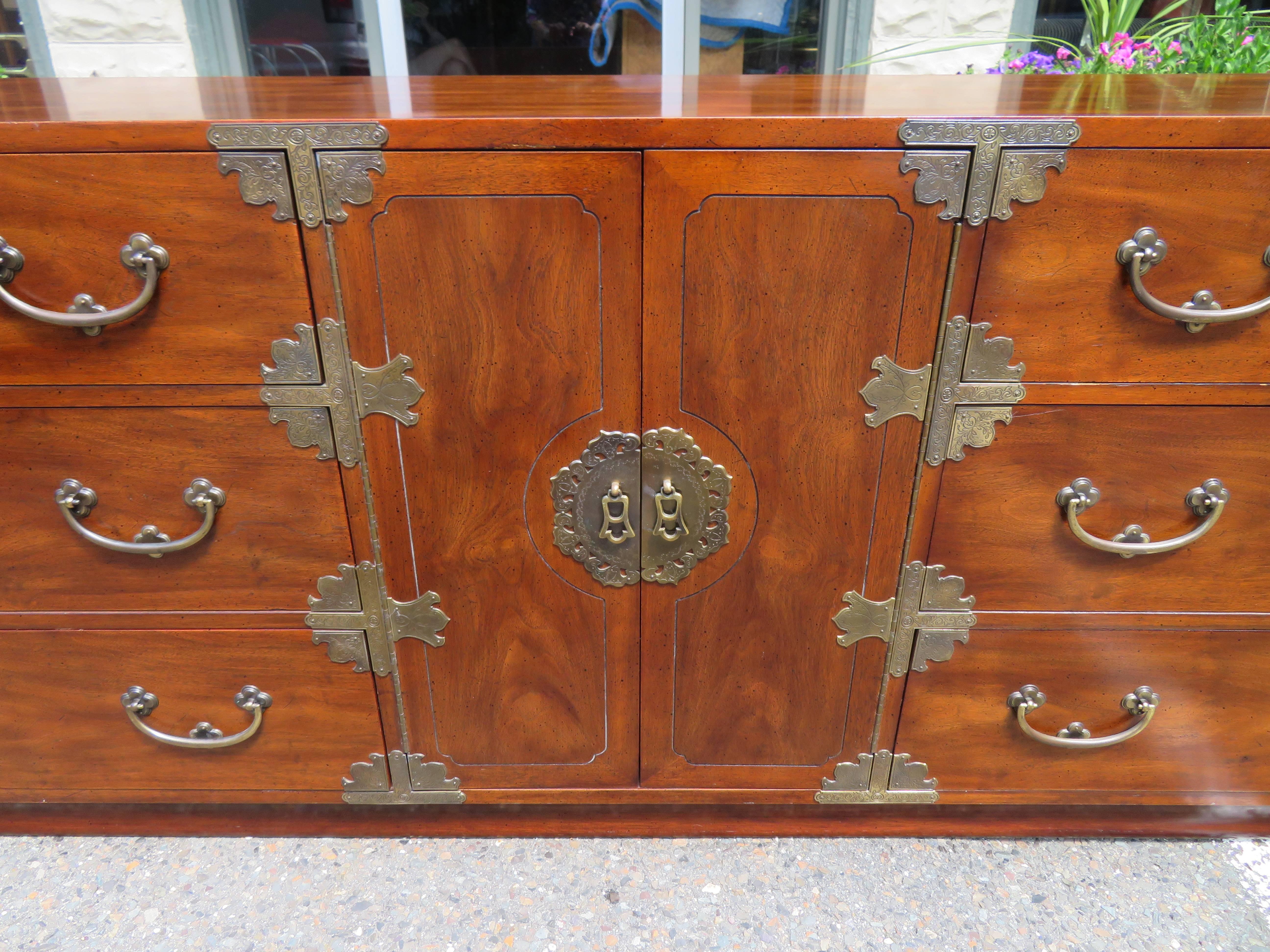Gorgeous Mid-Century chinoiserie campaign credenza or long dresser by Henredon Fine Furniture. This credenza features clean, sleek Mid-Century design with an Asian flair. It offers ample room for storage with 9 deep drawers. We love the stylish