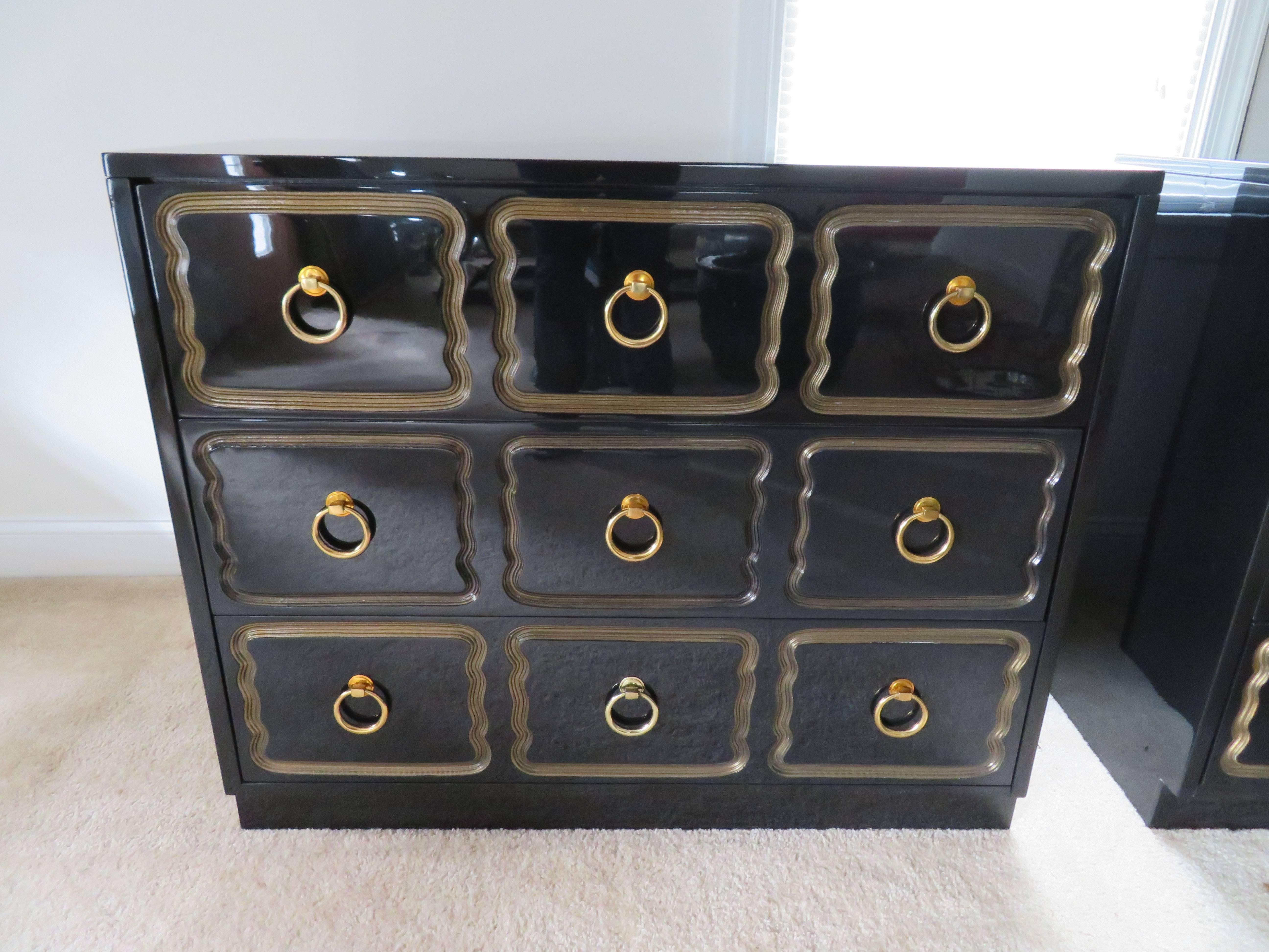Excellent pair of Dorothy Draper Espana rectangular chests with new glossy black lacquer finish. Large brass ring pulls adorn the centers of the nine wavy gold rimmed drawers. The super high gloss black lacquer finish has been expertly refinished