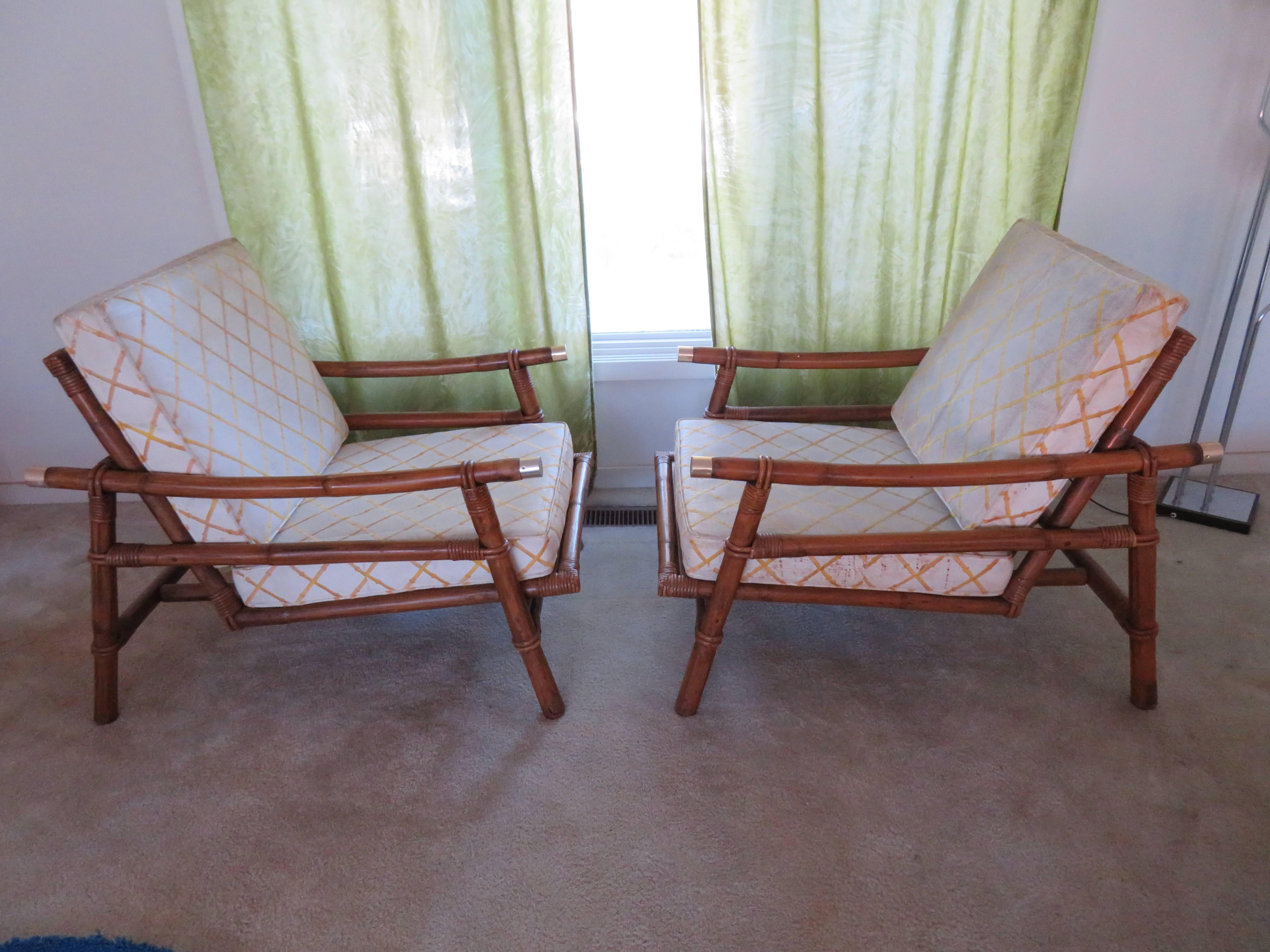 An exceptional pair of vintage Campaign style lounge chairs with matching ottomans. Stout rattan and hardwood frame with a beautiful raffia seat back. Fabulous design, quality and craftsmanship. Aged to absolute perfection the frames are in fabulous