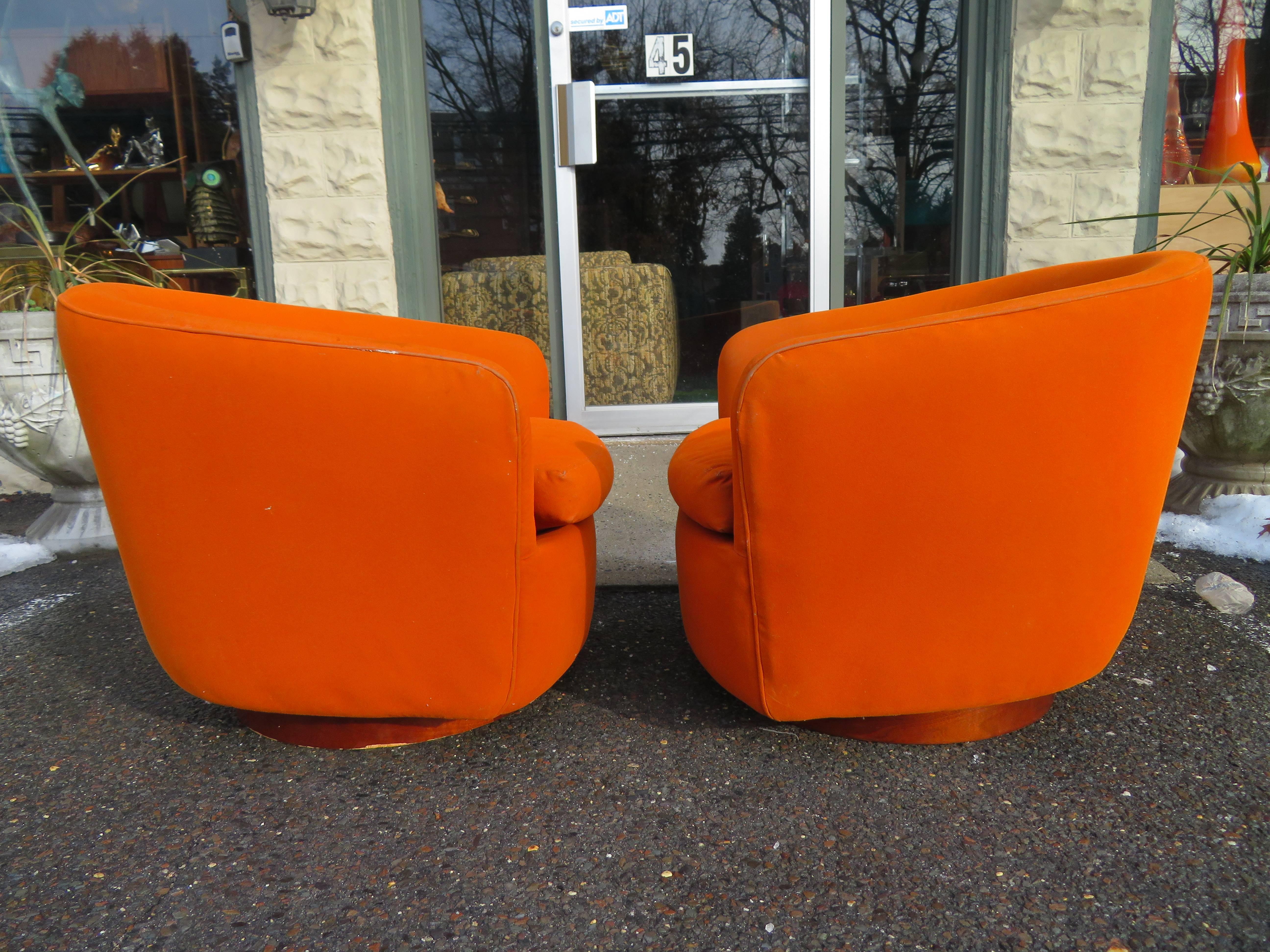 Lovely pair of Milo Baughman for Thayer Coggin tilt and swivel lounge chairs with round walnut Plinth Bases. This pair retains their original orange fabric and will need to be re-upholstered. We love the tilt swivel mechanism on these and so will