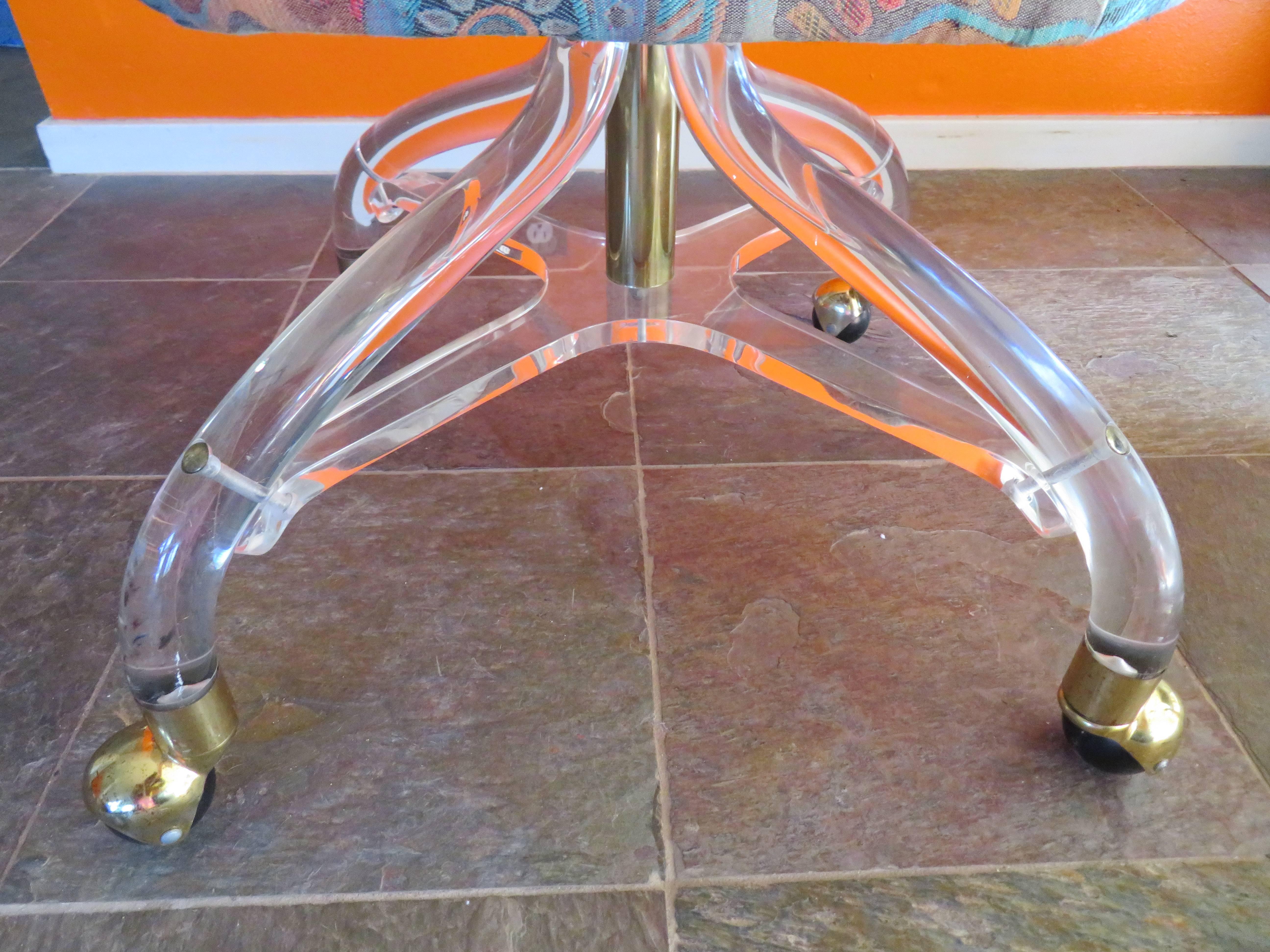 Stunning Lucite rolling stool. This lovely piece is in very nice vintage condition and rolls smoothly. The upholstery is dated and re-upholstery is recommended.