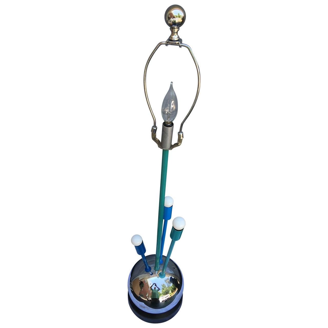Mid-Century Modern table lamp in the style of Sputnik.
This tall and shiny table lamp has a chrome ball base with newly powder coated teal/blue metal blue stems with small white bulbs and a center globe stalk. The lamp is modern and bright and will