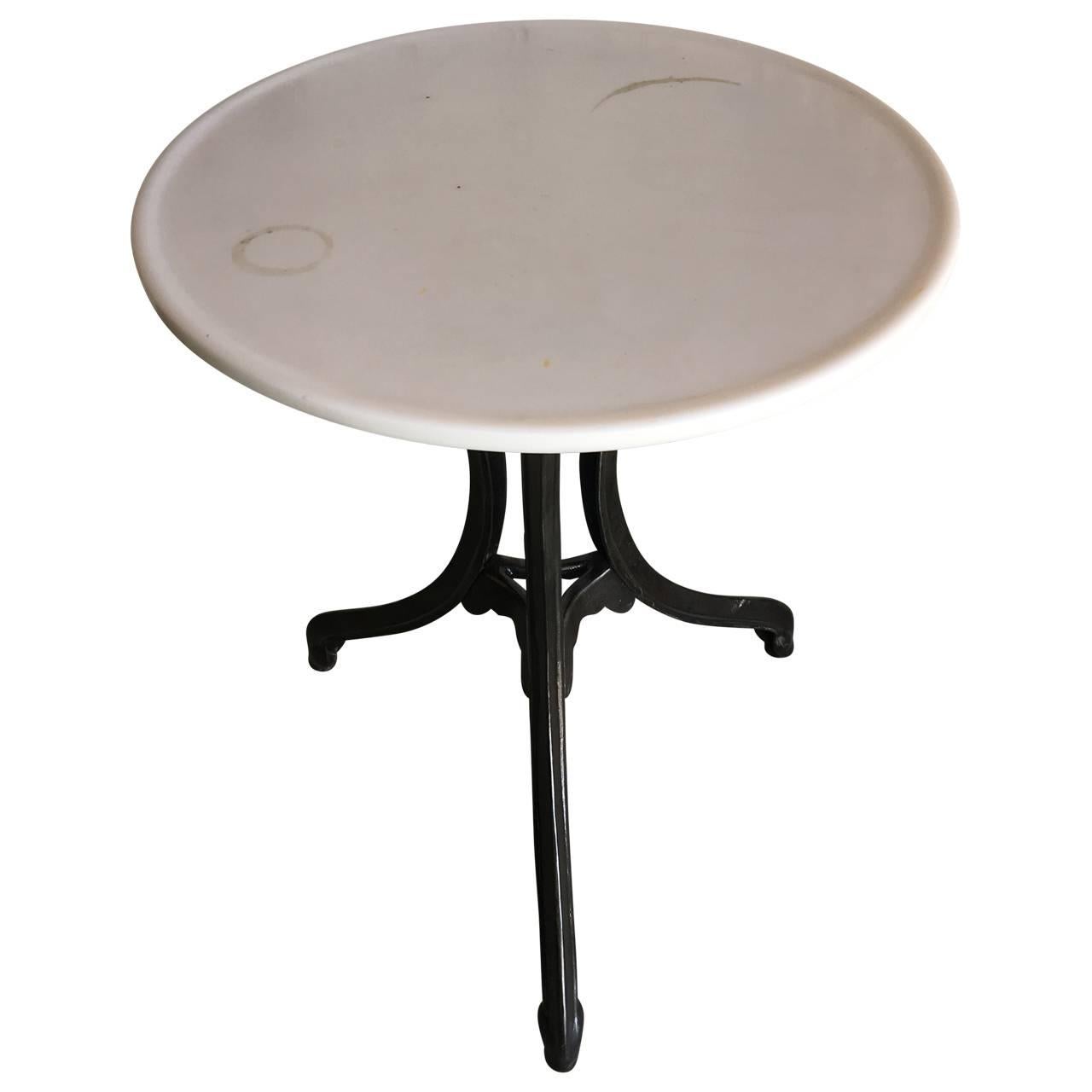 Bistro cast iron cafe table with rare Vitrolite tabletop. 
Vitrolite was an opaque pigmented glass manufactured by Pilkington Brothers in the United Kingdom. It was made by The Vitrolite Company (1908–1935) and Libbey-Owens-Ford (1935–1947) in the