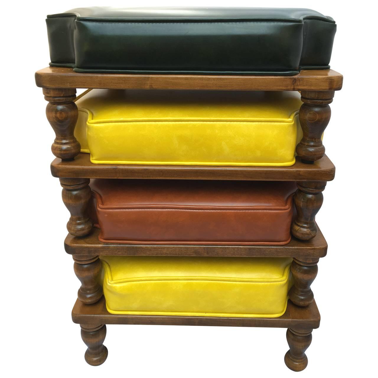 Cool set of four Ethan Allen stacking ottomans from the 1970s. The original Naugahyde cushions are very versatile in black, red and yellow. They sit atop a medium wood finish. 

Total height stacked is 24.5 inches.