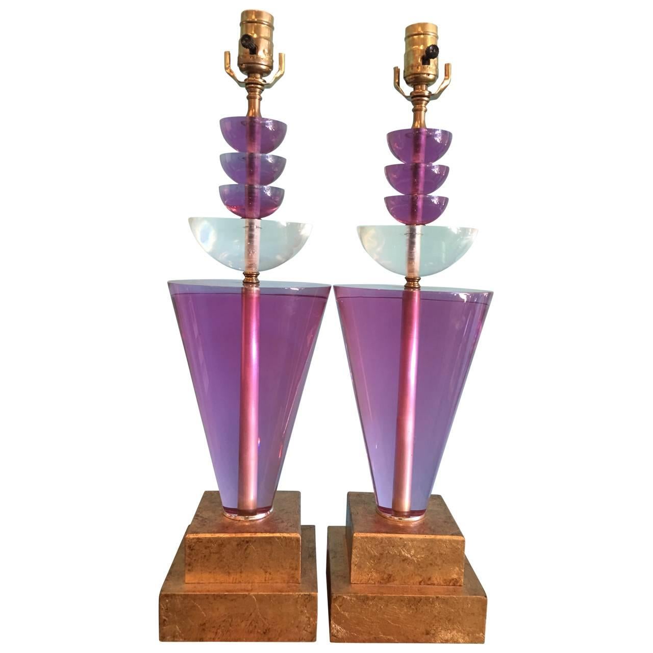 A stunning pair of purple lucite lamps on gilded wooden base.