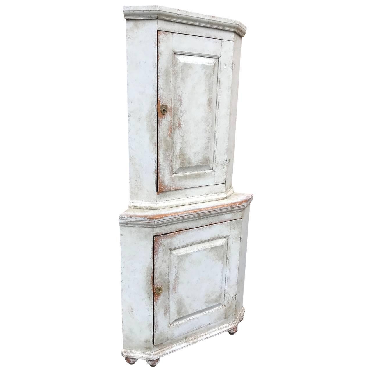 Gustavian one-piece corner cabinet with lower and upper shelved compartments, in Gustavian light blue paint.