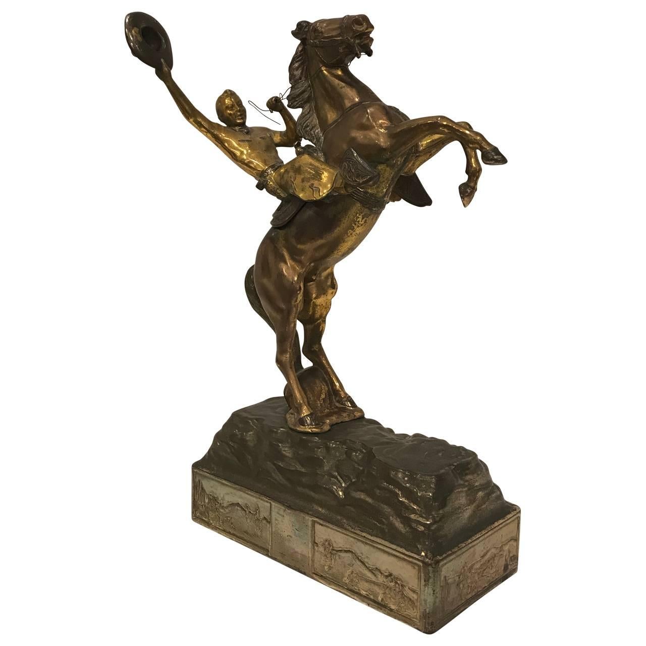 Gilt brass sculpture on stand, depicting a celebrating cowboy on a wild horse with great patina.