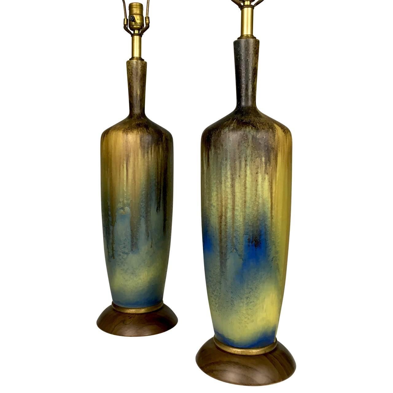 A fabulous pair of large Mid-Century, 1950s table lamps. 
Beautiful textured volcanic drip.
Glaze ceramic form with matte glaze color. Molten yellow, brown, blues on original walnut metal base.
Excellent Original Condition. Excellent wiring and