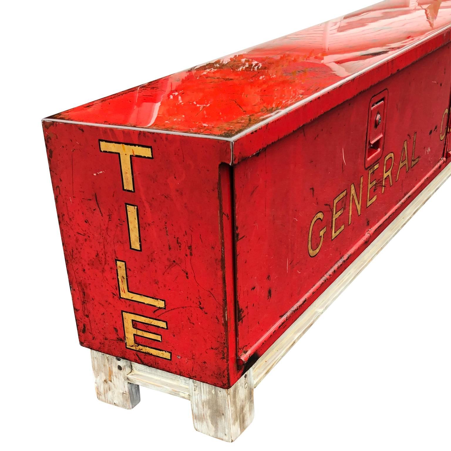 Long red and liquid-glass covered Industrial bench.

This re-purposed general construction tool box from a truck has been completed clean and covered in a thick coating of liquid glass. The wooden base is custom-made and makes this box into a