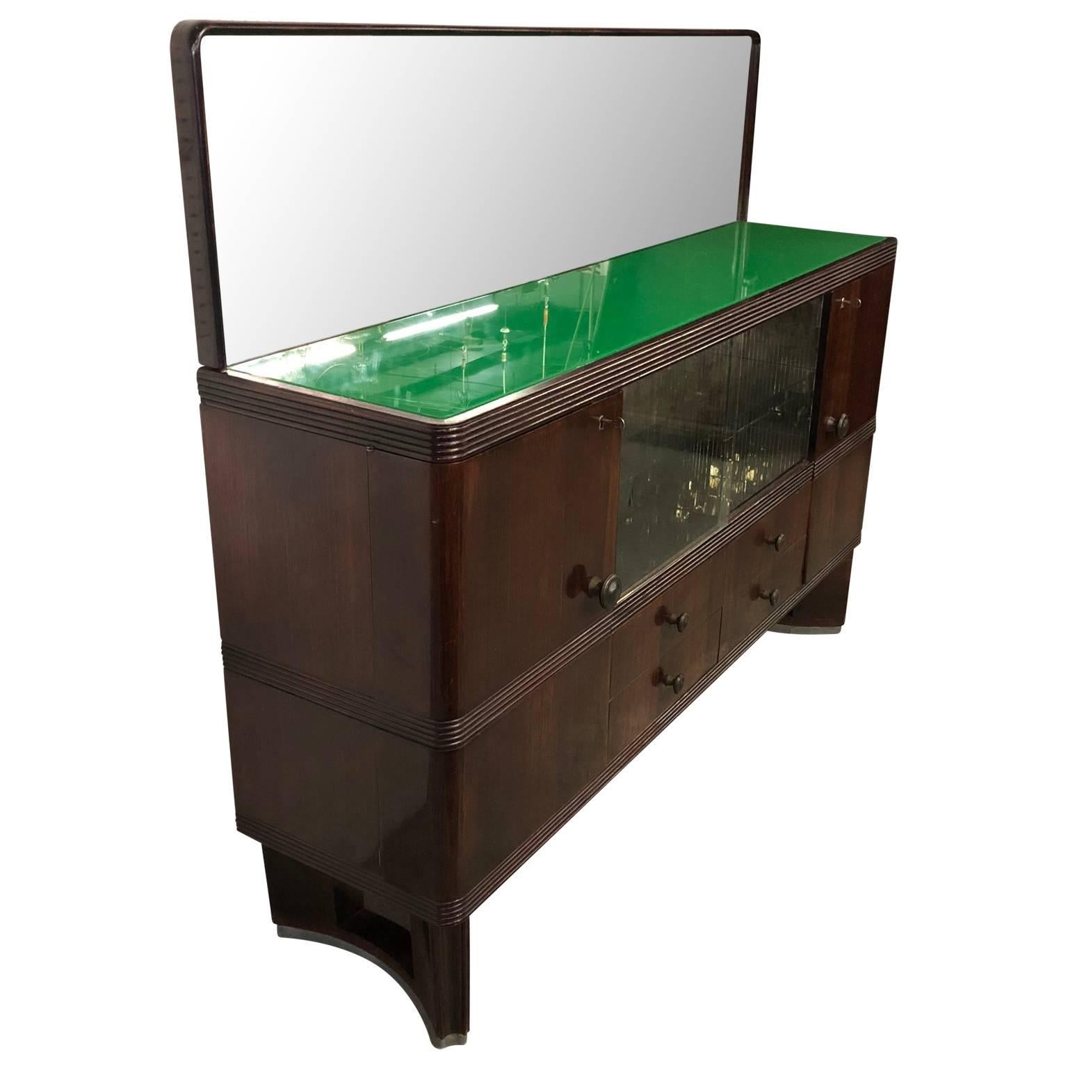 Vintage Italian Art Deco sideboard.

The sideboard has two glass shelf with mosaic-mirrored veneered sides. The green glass top and the rear mirror has circular decorations. The two side doors opens to two separate dry bar compartments. All hardware