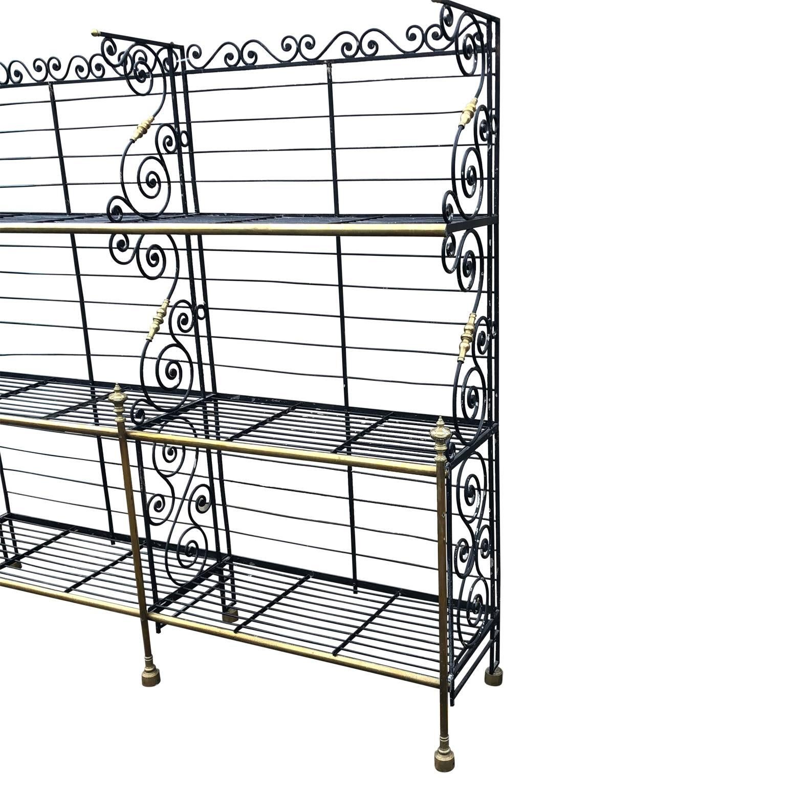 Large antique bakers rack made of black painted wrought iron and brass with great patina.
This particular rack has 3 especially rare decorated brass finials. One corner is rounded which is also rare and should be helpful in a kitchen installation
