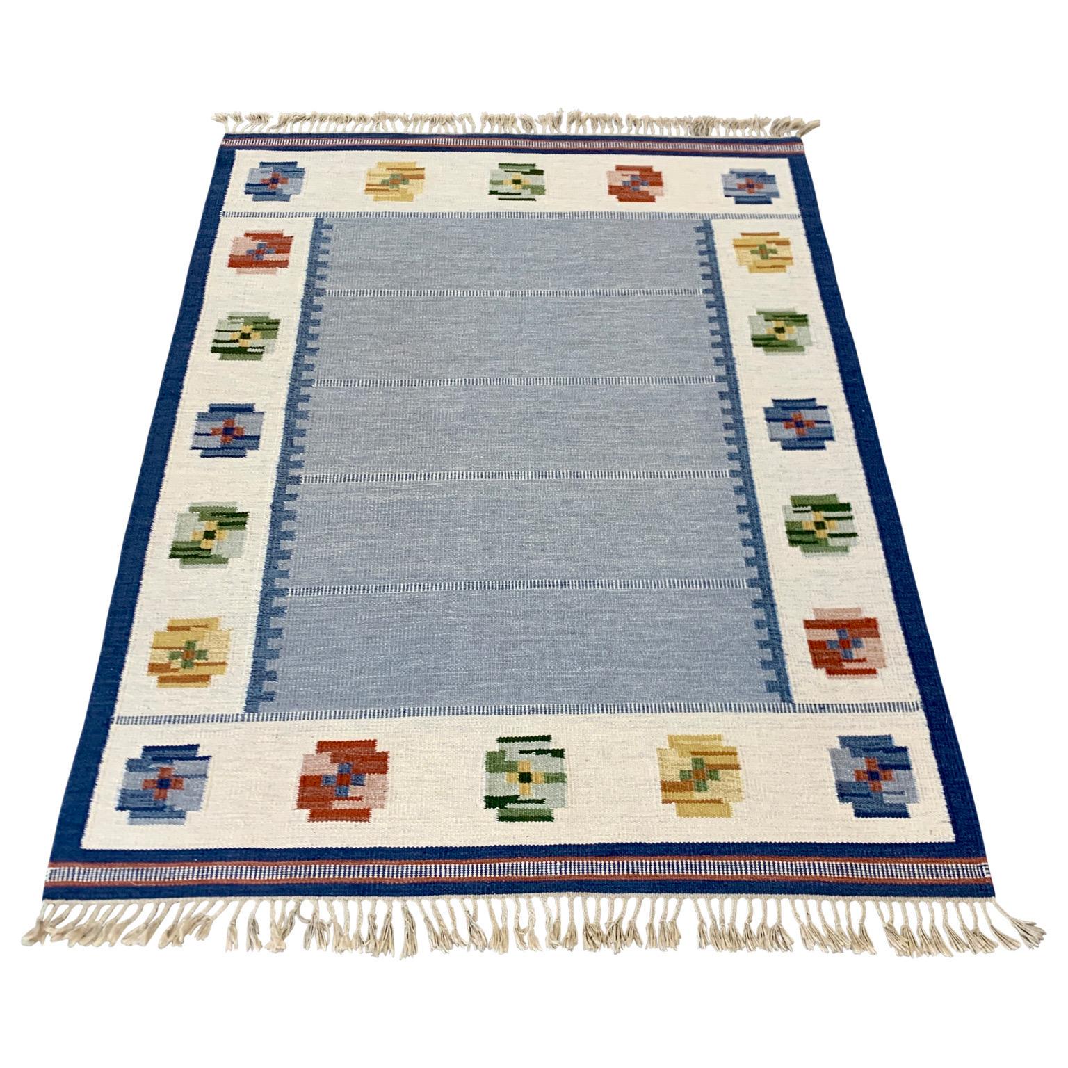 A Mid-Century Modern vintage handmade Swedish carpet in wool featuring a geometric pattern. This blueish colored Scandinavian rug dates between 1950 and 1970. The tradition of quality handwoven Rölakan carpets and rugs as well as modern style from