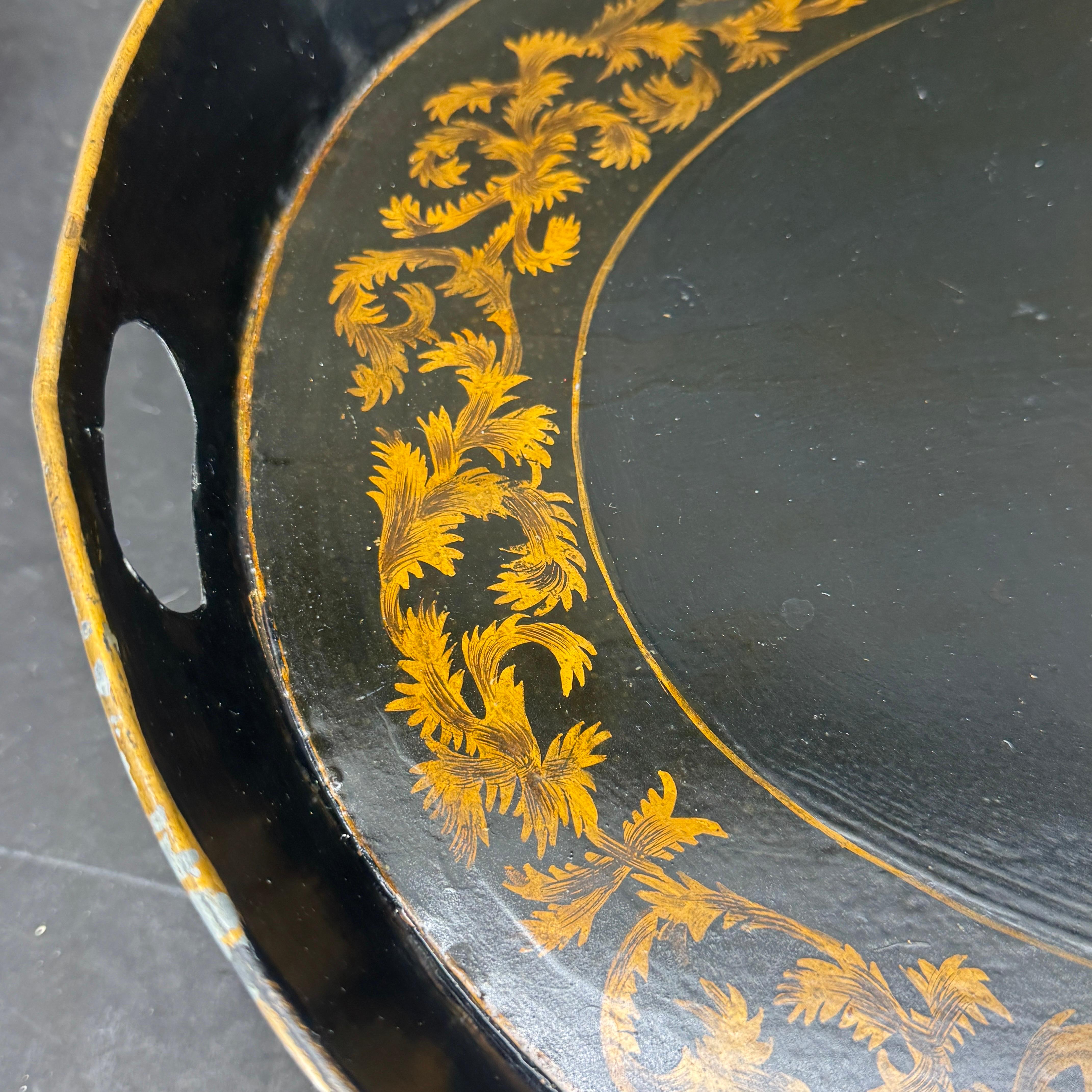 Ce plateau ovale peint en noir et doré est d'une ancienneté et d'une patine incomparables. Le plateau présente des feuilles dans un motif ovale. Tel qu'on le trouve en Suède, ce plateau métallique est utilisé sur une table basse, sur un ottoman ou