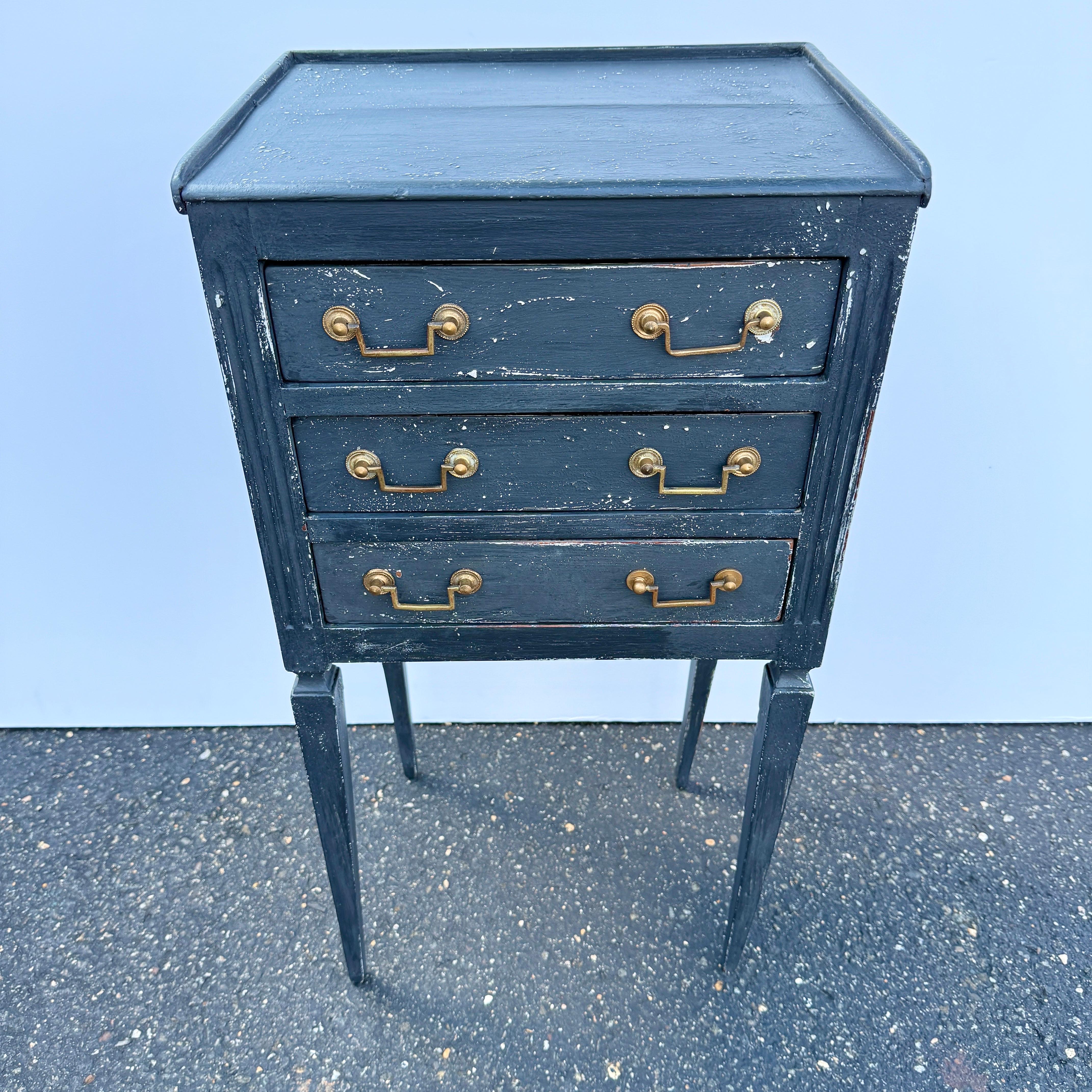 Cette table d'appoint de style classique comporte trois tiroirs avec des ferrures en laiton d'origine. La table a été peinte à la main dans un ton de bleu gustavien et a été construite en bois massif. Cette table de nuit apporte un charme vintage et