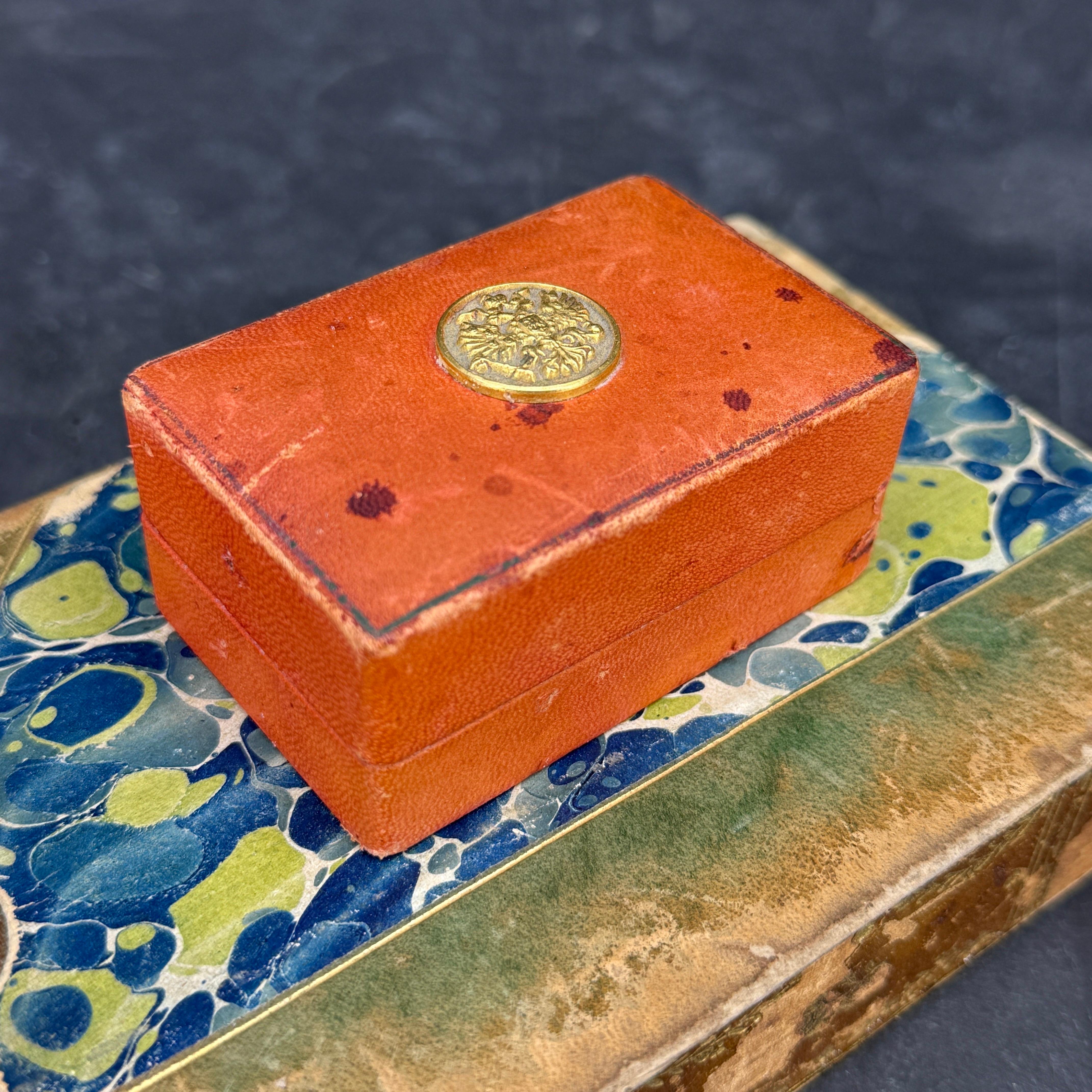 Très charmante petite boîte rectangulaire italienne du milieu du siècle en cuir avec un médaillon doré d'un aigle à deux têtes sur le couvercle. L'intérieur est également recouvert de cuir souple. Cette petite boîte peut être utilisée pour ranger