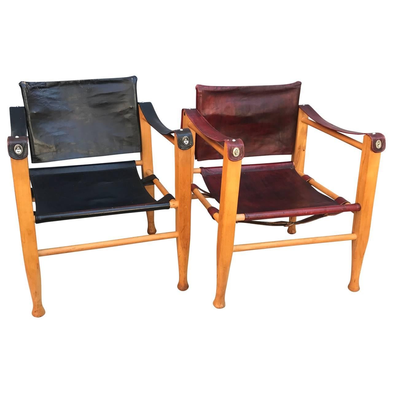 Two vintage Danish Safari chairs, one in thin black leather and one in thin red leather. Both seat has original backing to the leather for strength.

 