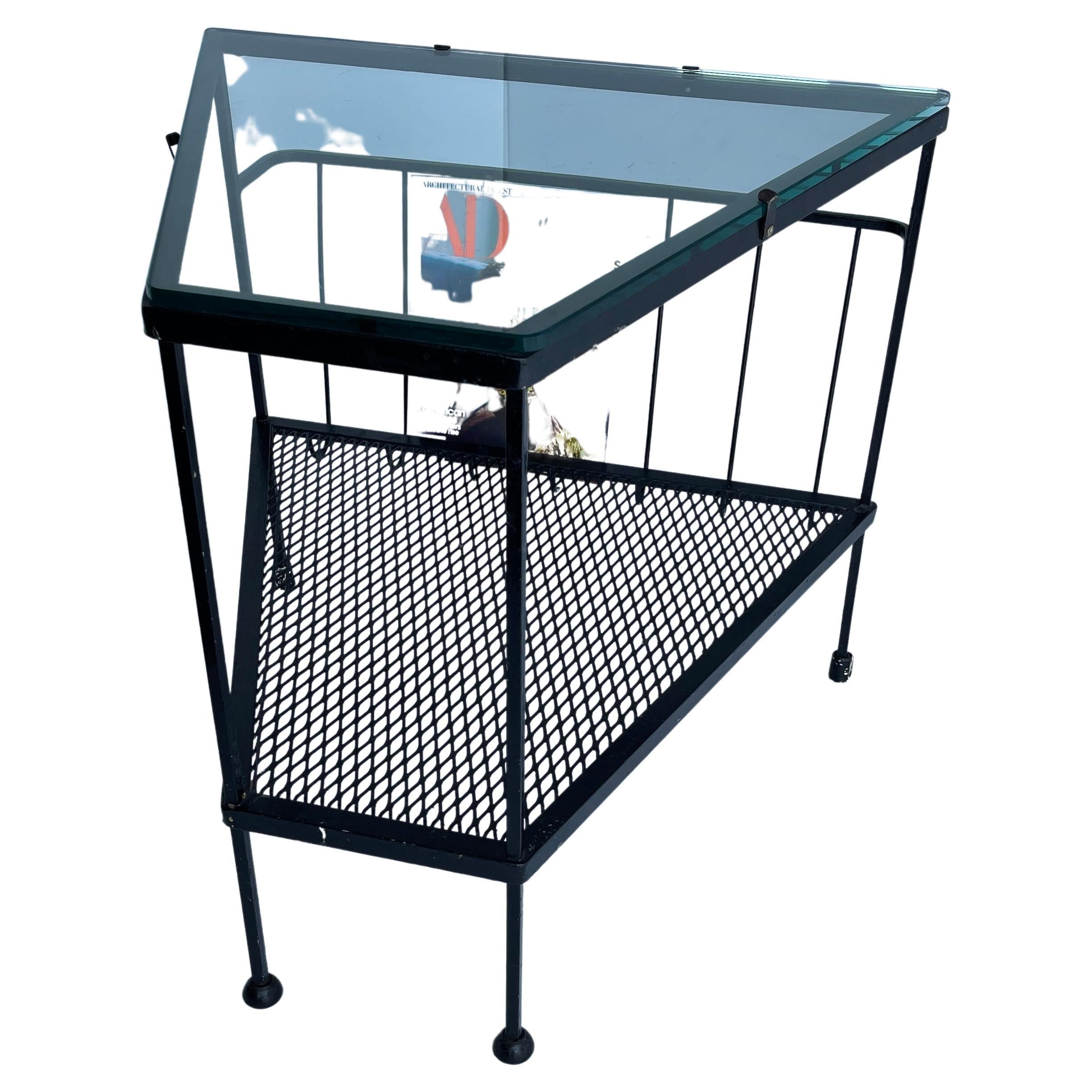Black metal side table with glass top, Mid-Century Modern.
This is a fun and functional table and magazine rack. The solid metal table has the glass top with second tier that holds books or anything that you can display. The back side is open metal
