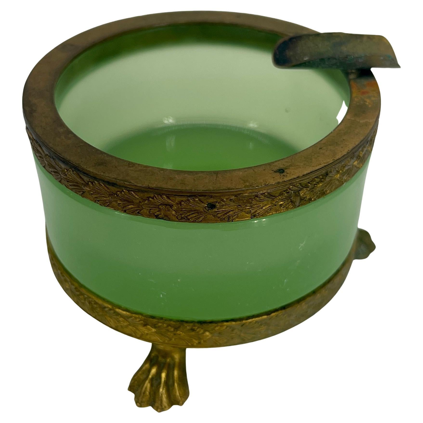 Exquisite French green opaline ashtray, circa early 1920's. 
This petite round green opaline ashtray is flanked by three brass splay feet. It is elegant and graceful. The opaline glass is in very good condition and is a perfect addition to a bar or
