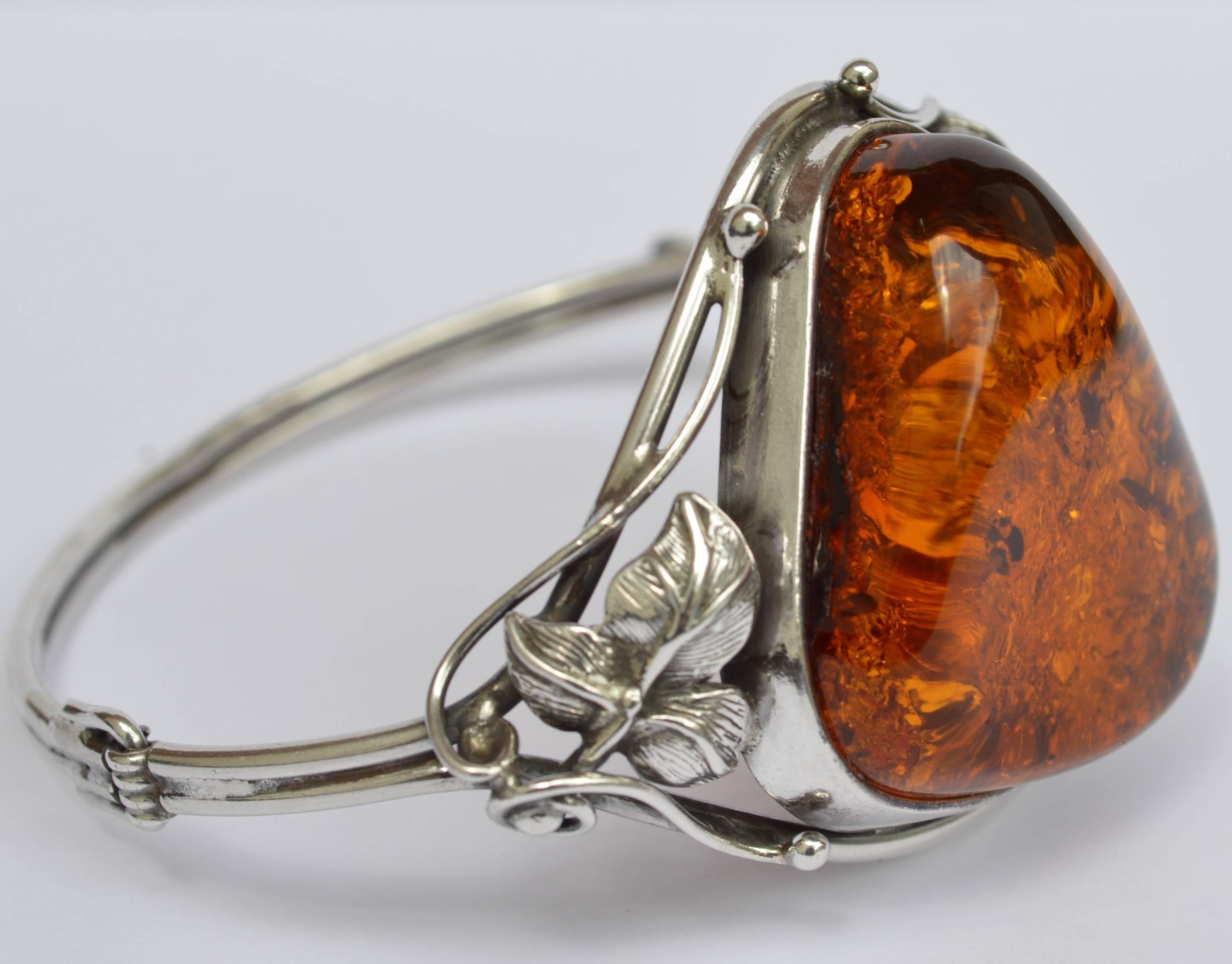 Danish Mid-Century sterling silver bracelet with large amber stone.
This is a beautiful sterling silver bracelet with a large amber stone. Silver leaves of three flank each side of this gorgeous and rather large piece of amber. 
Size 7.
Amber