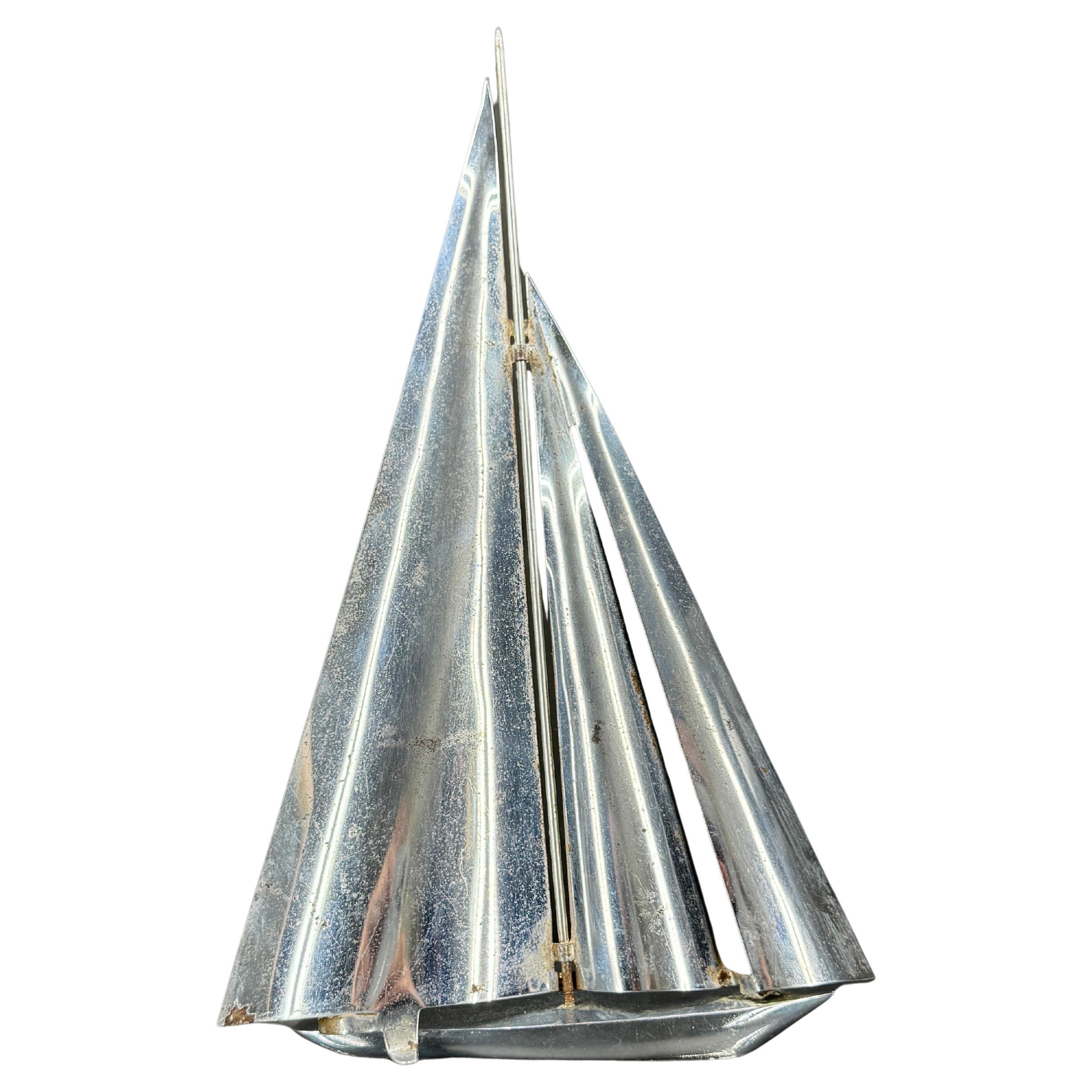 Incantevole barca a vela cromata su un supporto in lucite. Vediamo questo pezzo nautico esposto su una libreria o come pezzo forte su una consolle, un tavolino o un tavolino da caffè. È un regalo meraviglioso anche per l'amante dell'oceano della tua