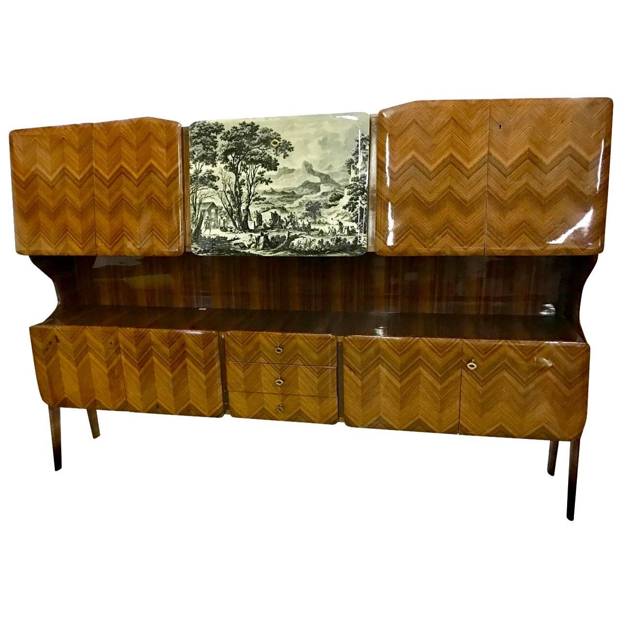 This rare credenza in the style of Gio Ponti and Piero Fornasetti by Vittorio Dassi was made in Milano in the early 1950s and before 1954.

The rosewood veneered wall unit can be used as a sidebord or an dry bar. The sideboard has a drop-down door