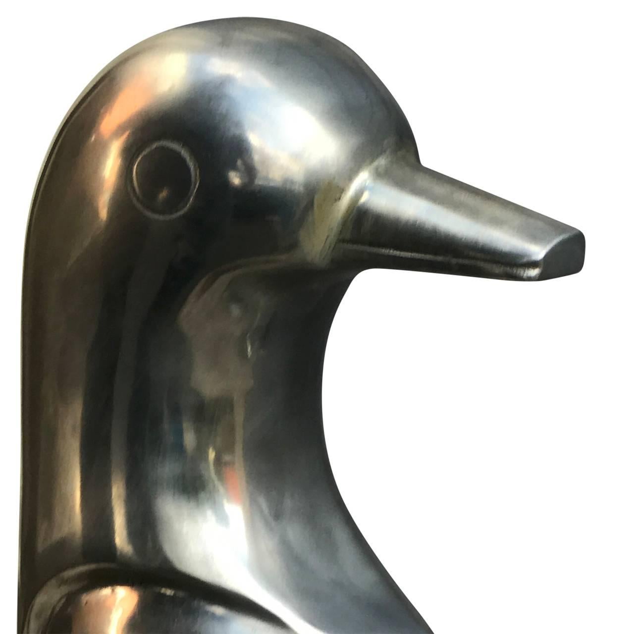 Two aluminum emperor penguins, mother and daughter or father and son, on a black wooden base.