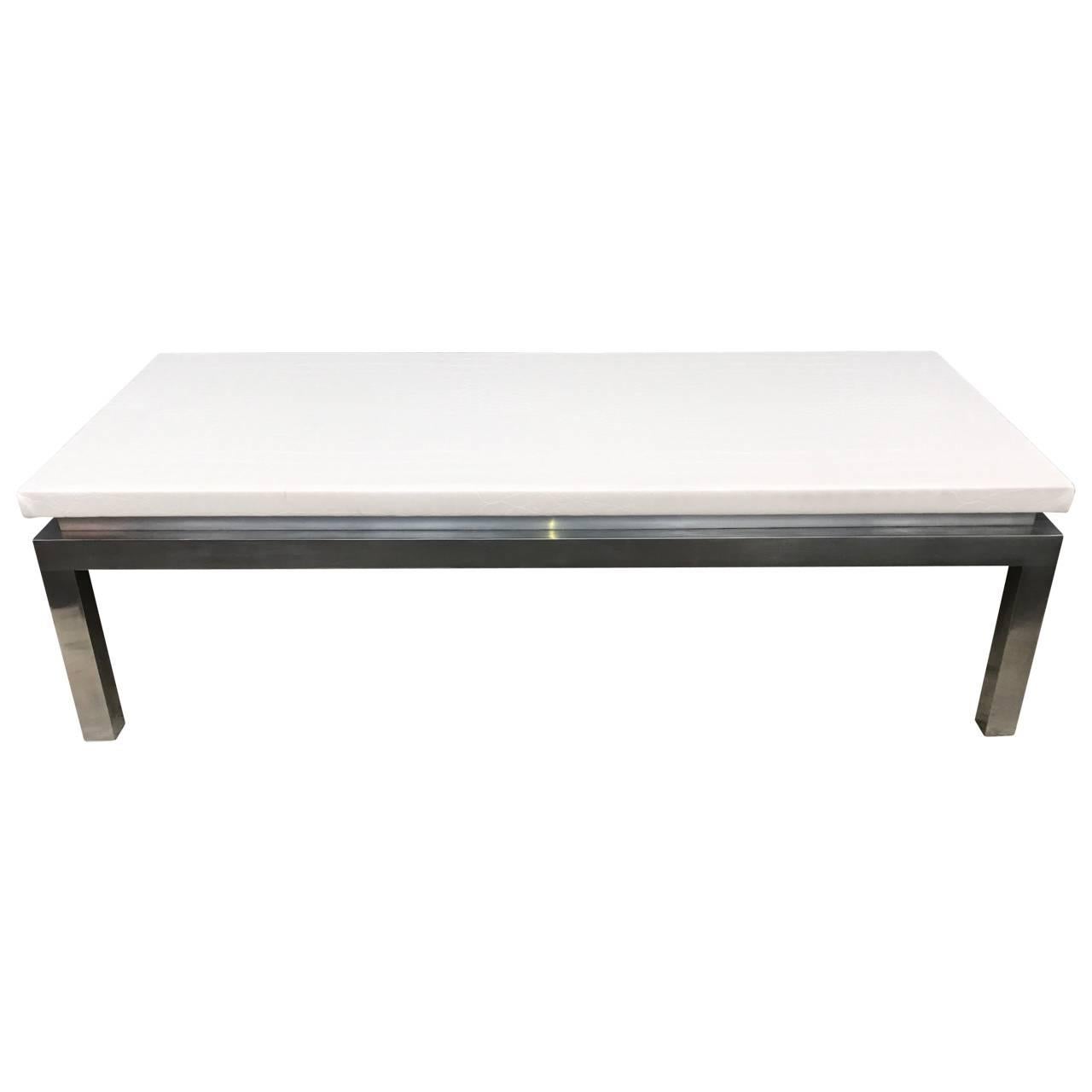 Solid stainless steel heavy two-piece base rectangular coffee table with thick white faux leather top.