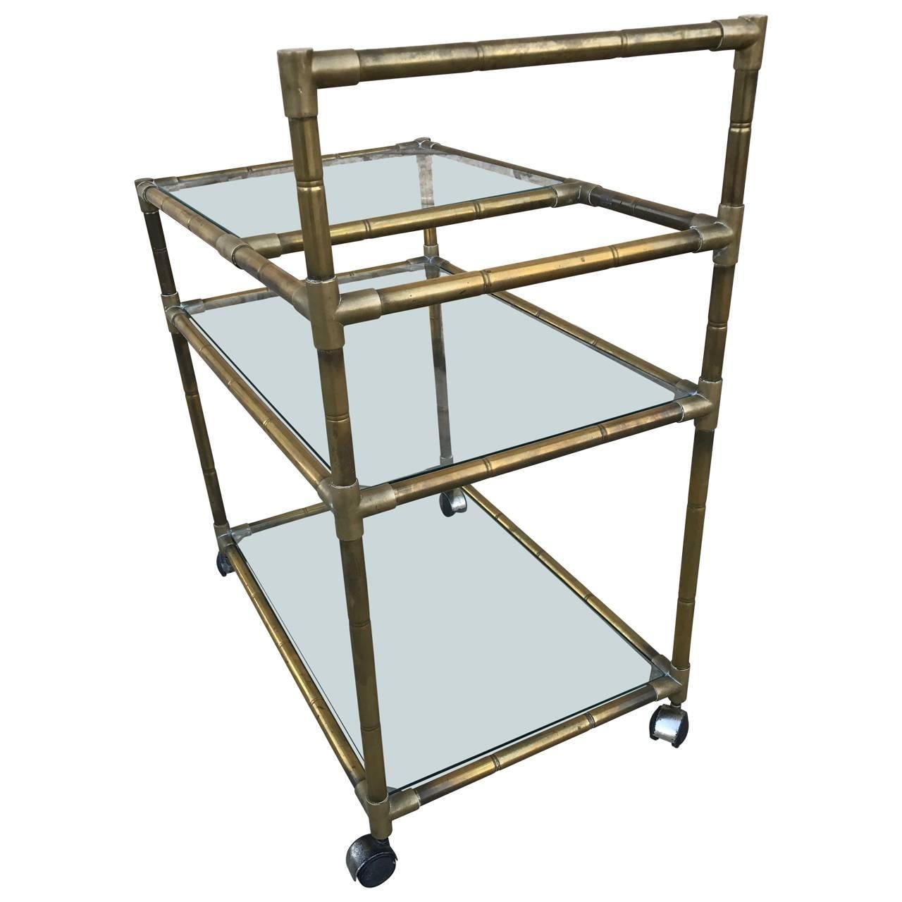 Charming English three-tier brass bar cart in faux bamboo style in great condition and untouched patina. Top shelf (height of 23.5) is split open for placement of bottles.