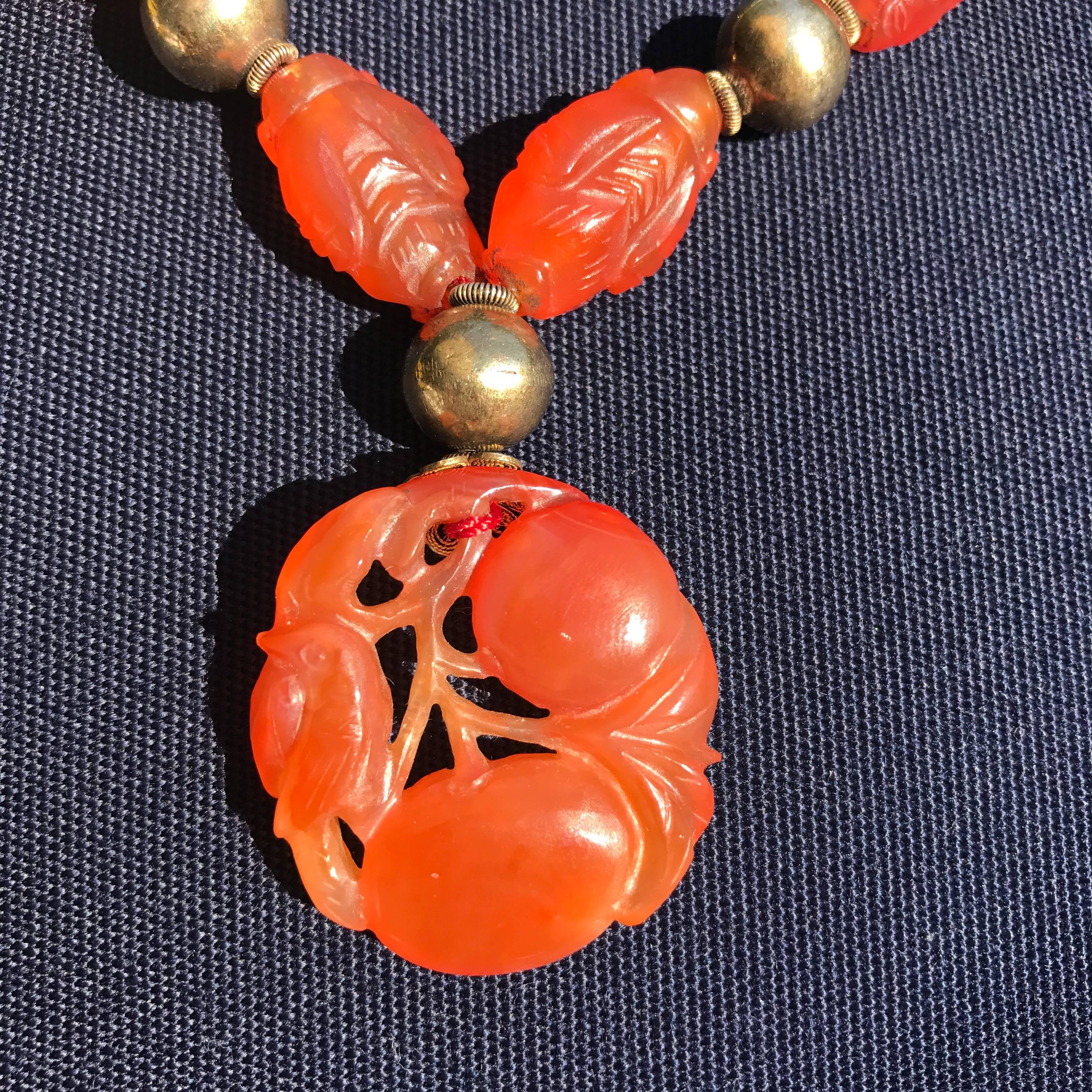 Antique necklace of gilded silver and carnelian stones depicting a parrot and choppy Chinese figure. Provenance to a American businessman living in China in the beginning of the 20th century.