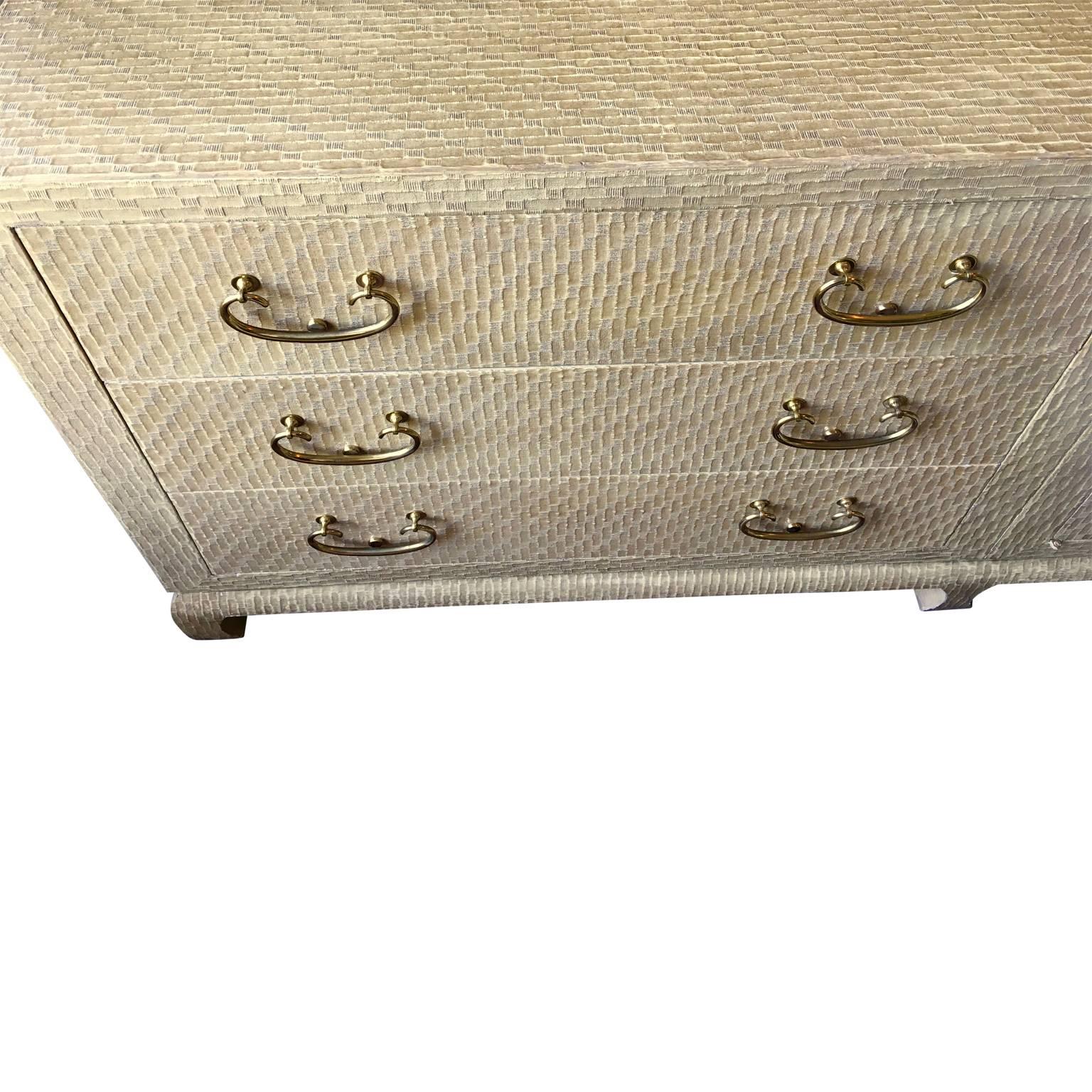 Baker Asian modern sideboard covered in lacquered grasscloth. Cabinet is from Bakers Far East Collection. Large brass escutcheons and brass pulls