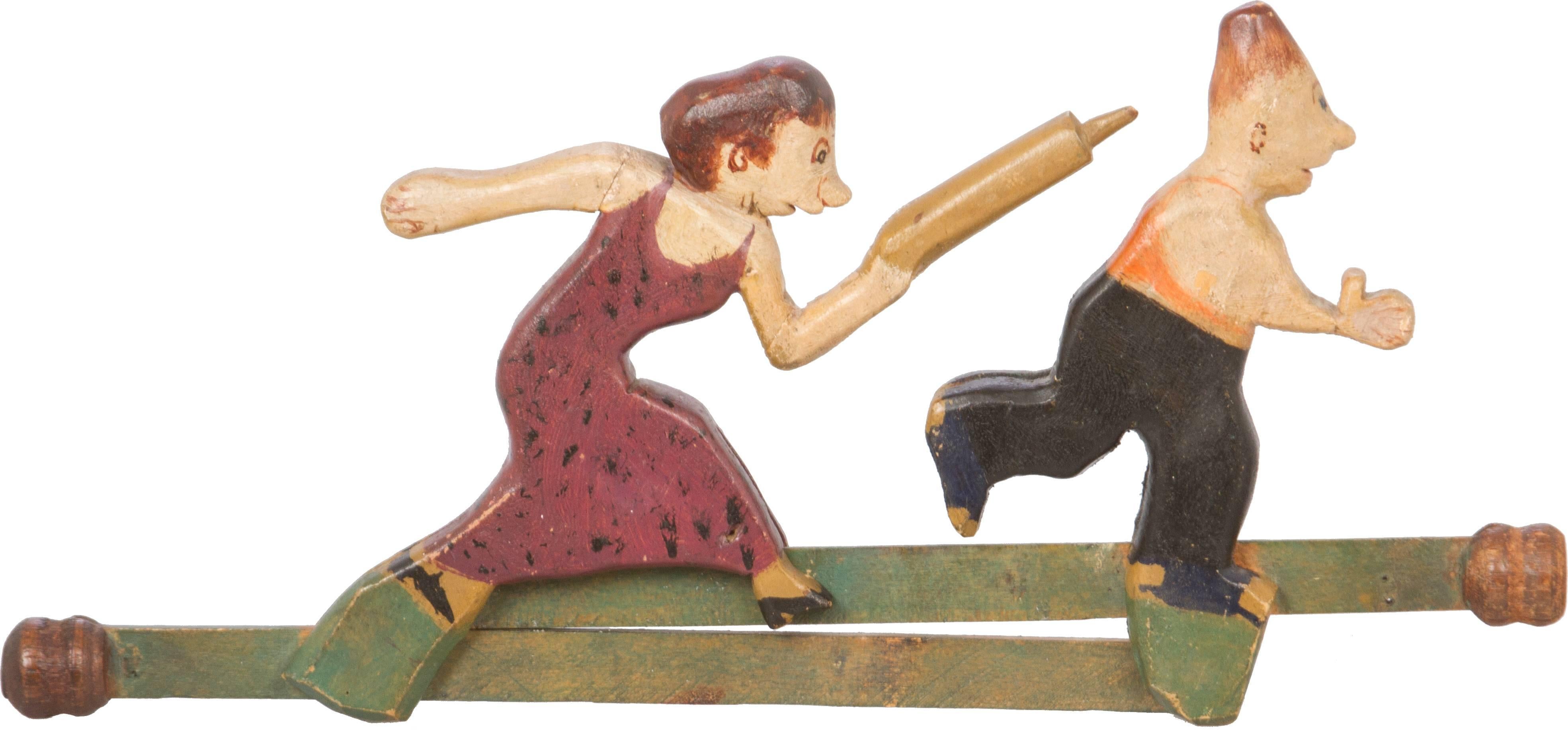 This is a one of a kind hand-carved toy of a wife, with rolling pin in hand, chasing her husband.