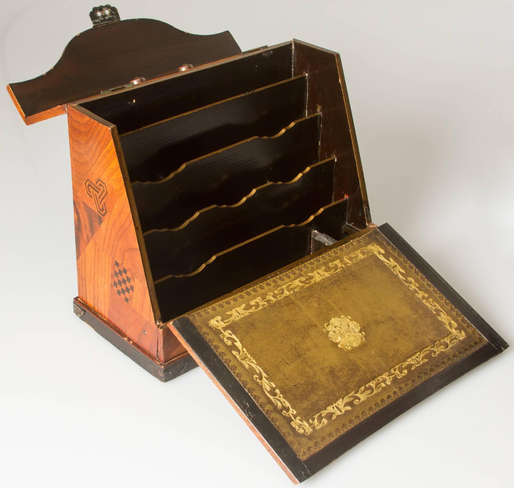 This is a beautiful traveling desk box. The interior contains space for brushes, pens and paper. The box front flips down to reveal a gold embossed leather interior.