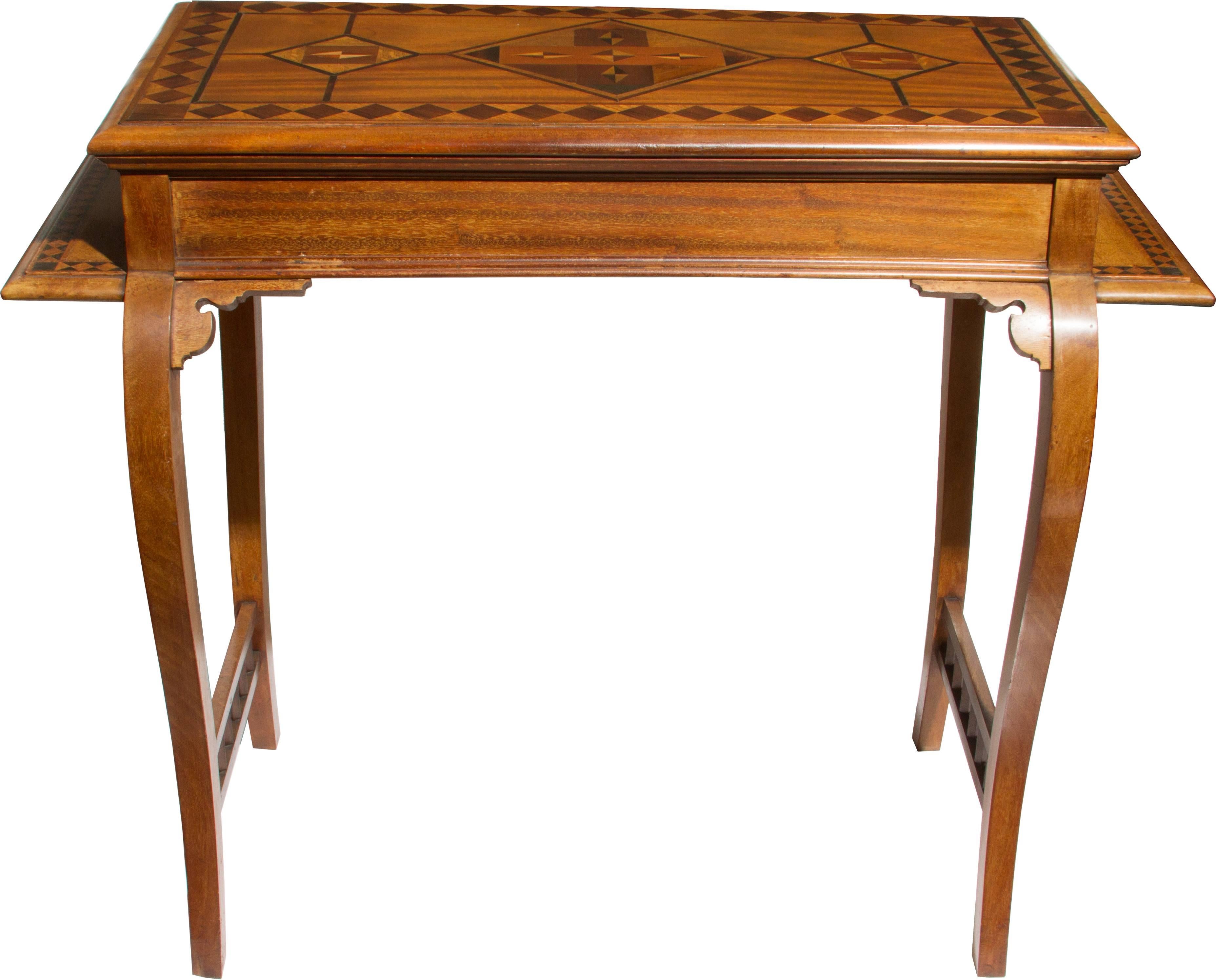 This handsome table has an interesting shape with an inlaid design on the side shelves as well as the top and fretwork between the legs.
