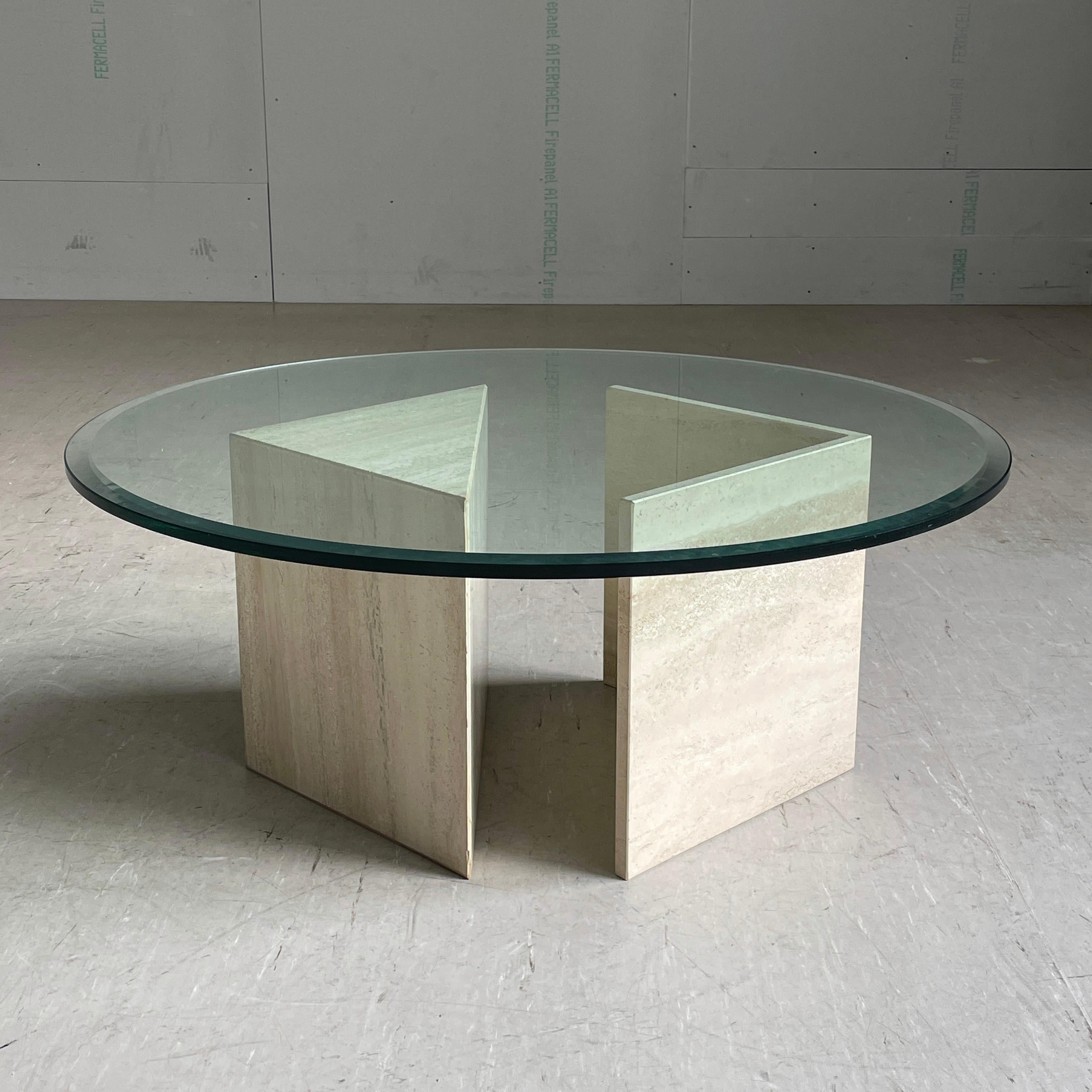 Table de salon en travertin des années 1970 avec plateau en verre. Plateau de table rond en verre posé sur un socle en pierre naturelle solide en deux parties. La lourde base en travertin peut être réglée en fonction des besoins, ce qui permet de