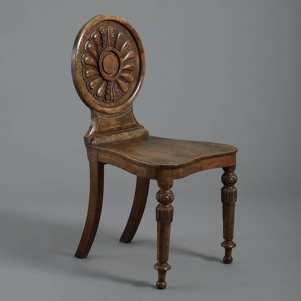 A fine and unusual pair of William IV pollard oak hall chairs, circa 1835.