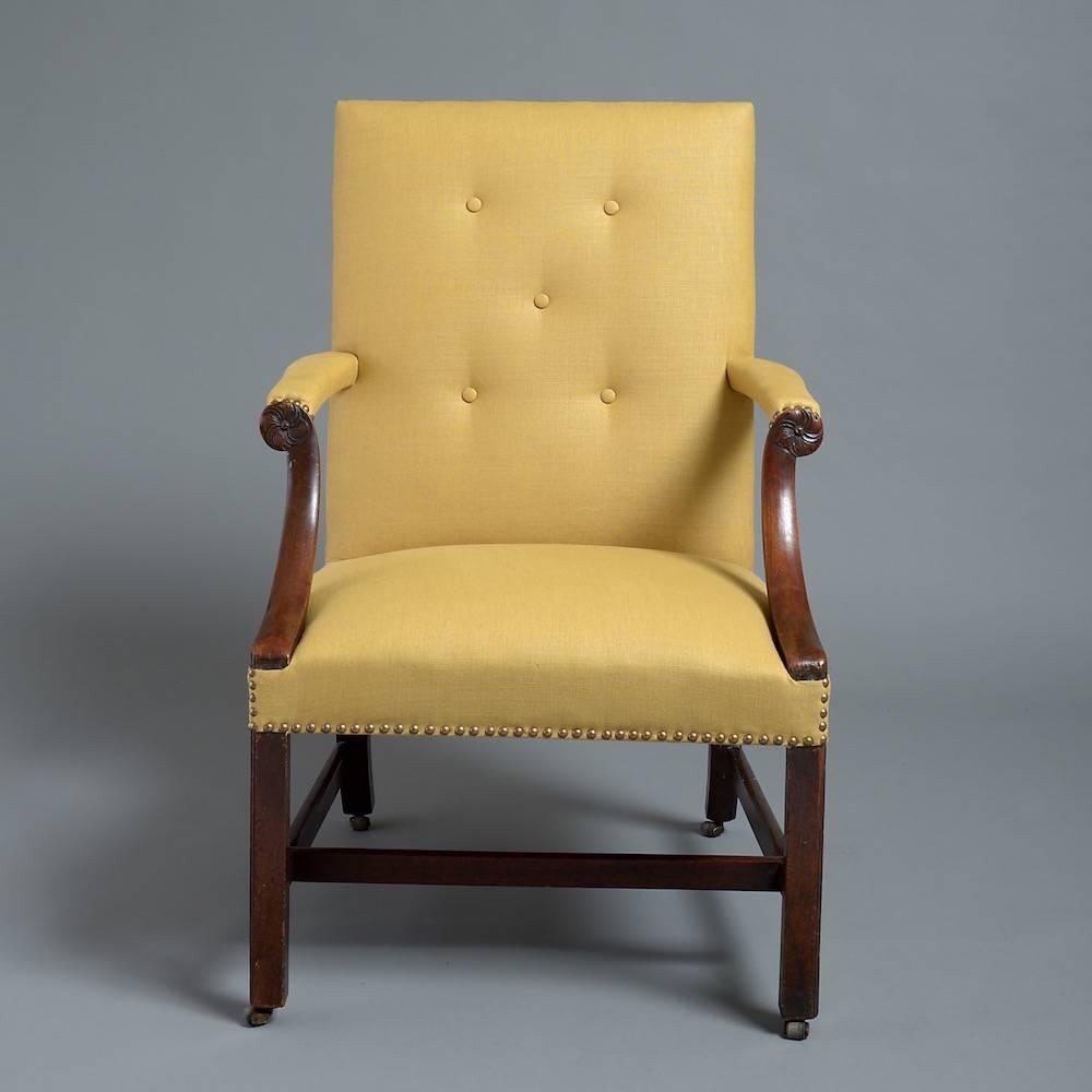 A large George III mahogany library chair, circa 1760. 

Upholstered in close-nailed yellow linen and the down sweeping arms headed by carved rosettes.