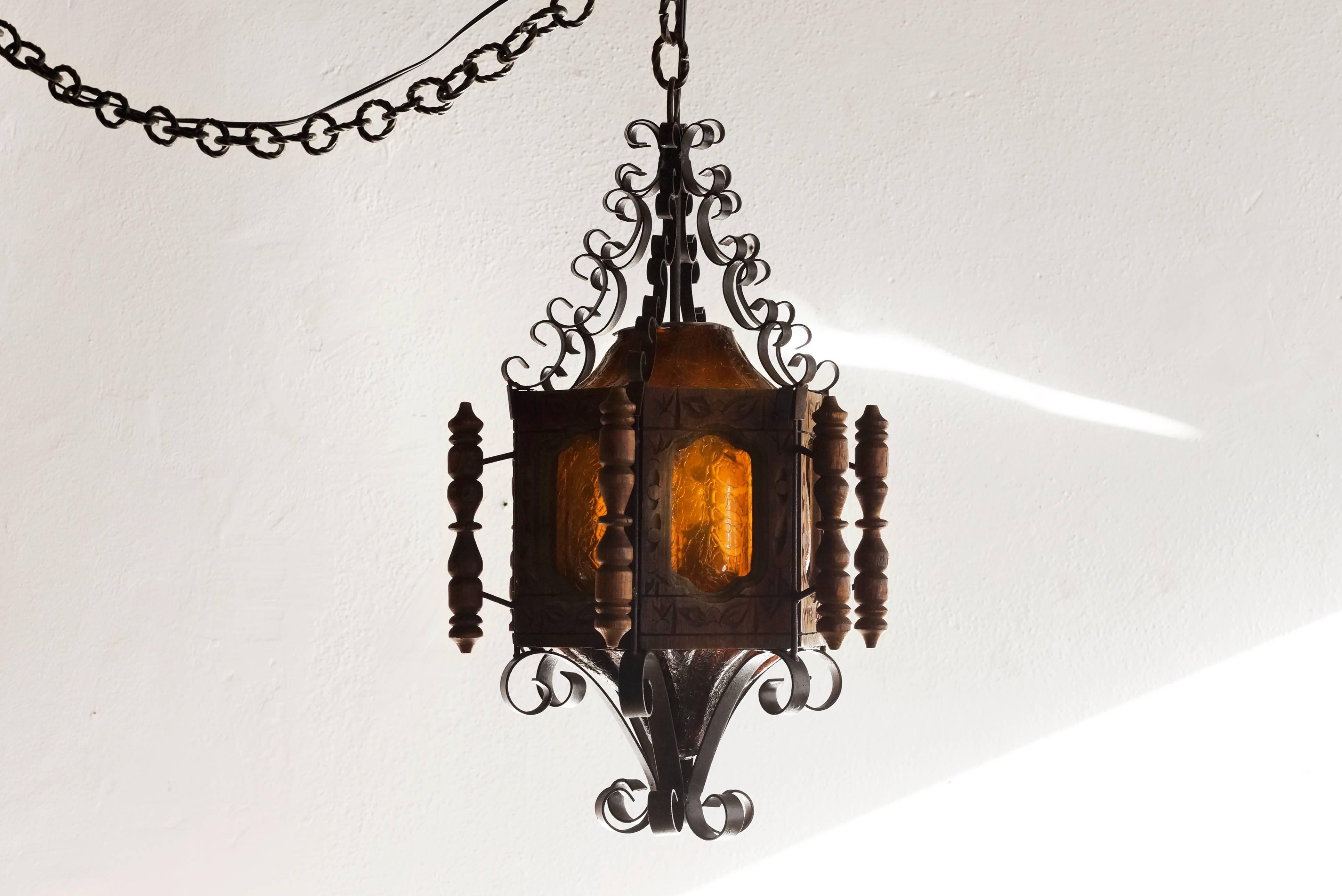 1960s Spanish revival pendant light of carved wood, wrought iron and tinted glass. This retro California fixture is fully-functional and ready to hang.

Dimensions: 28