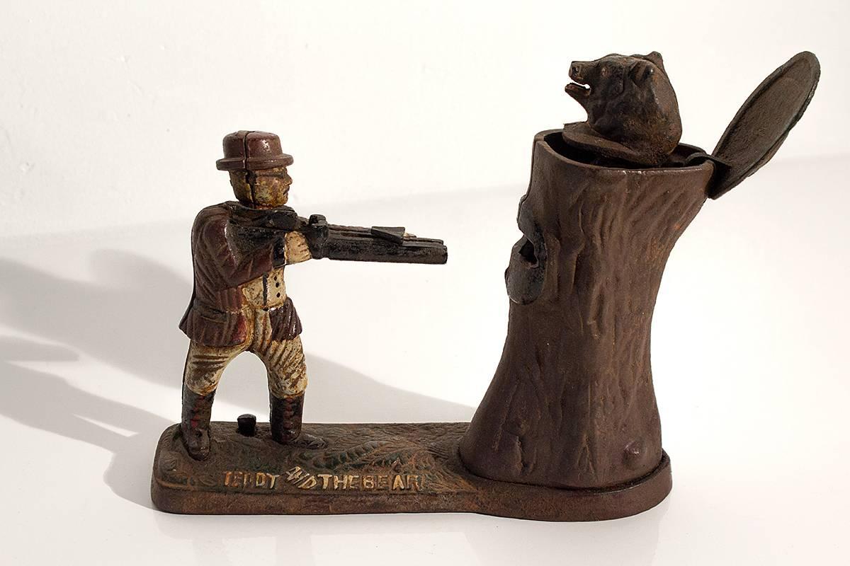 Mechanical bank featuring Teddy Roosevelt hunting bear. Fully functional cast iron collectible.
Push button on base release coin into the tree slot and the bear's head pops out.

